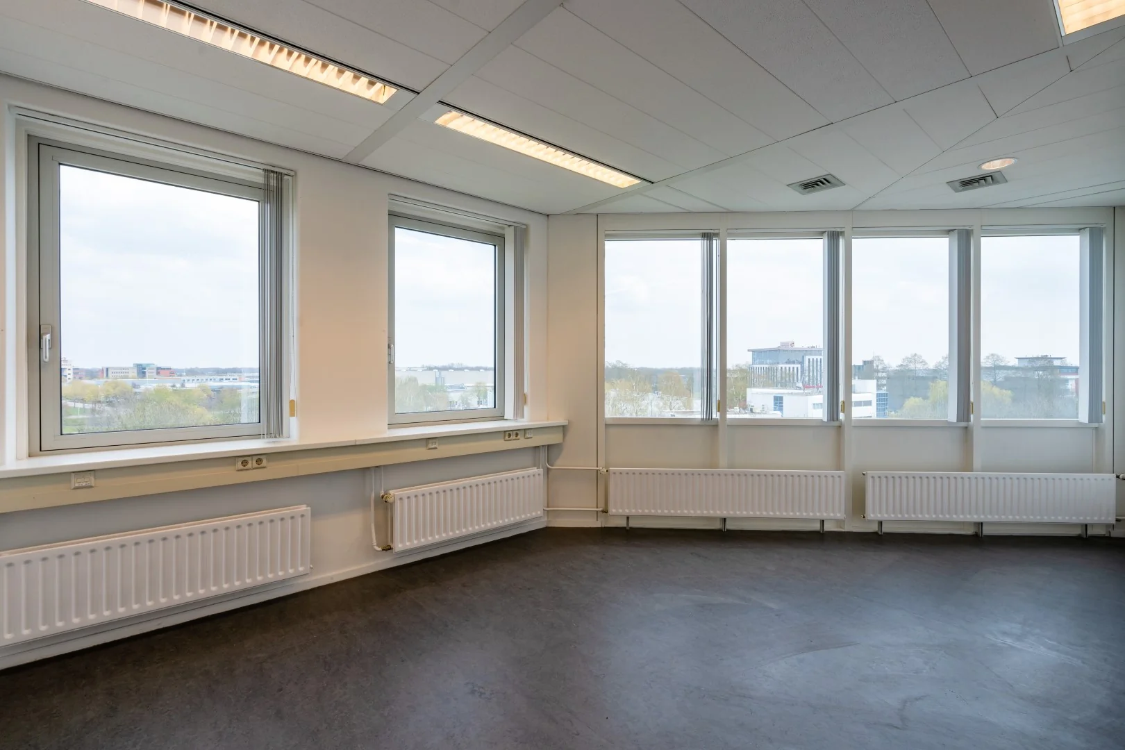 Licht kantoorruimte met grote ramen en uitzicht op bedrijventerrein aan de Printerweg.