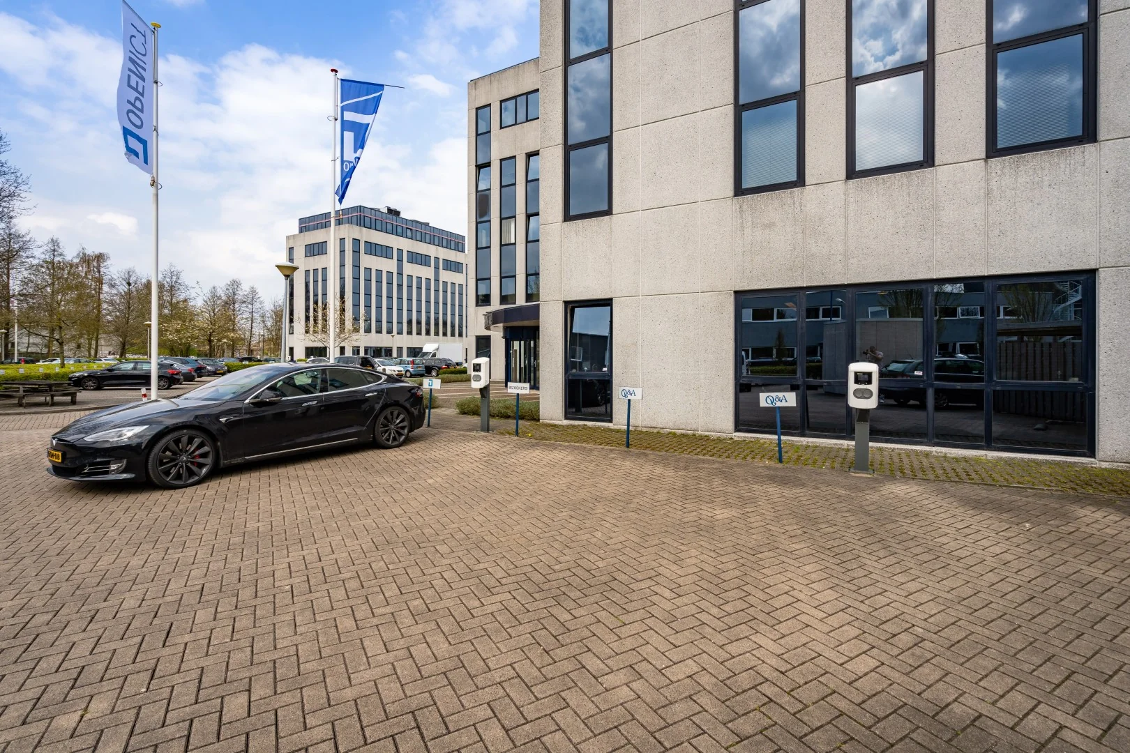 Zwarte elektrische auto parkeert bij laadpaal voor kantoorpand aan de Printerweg.