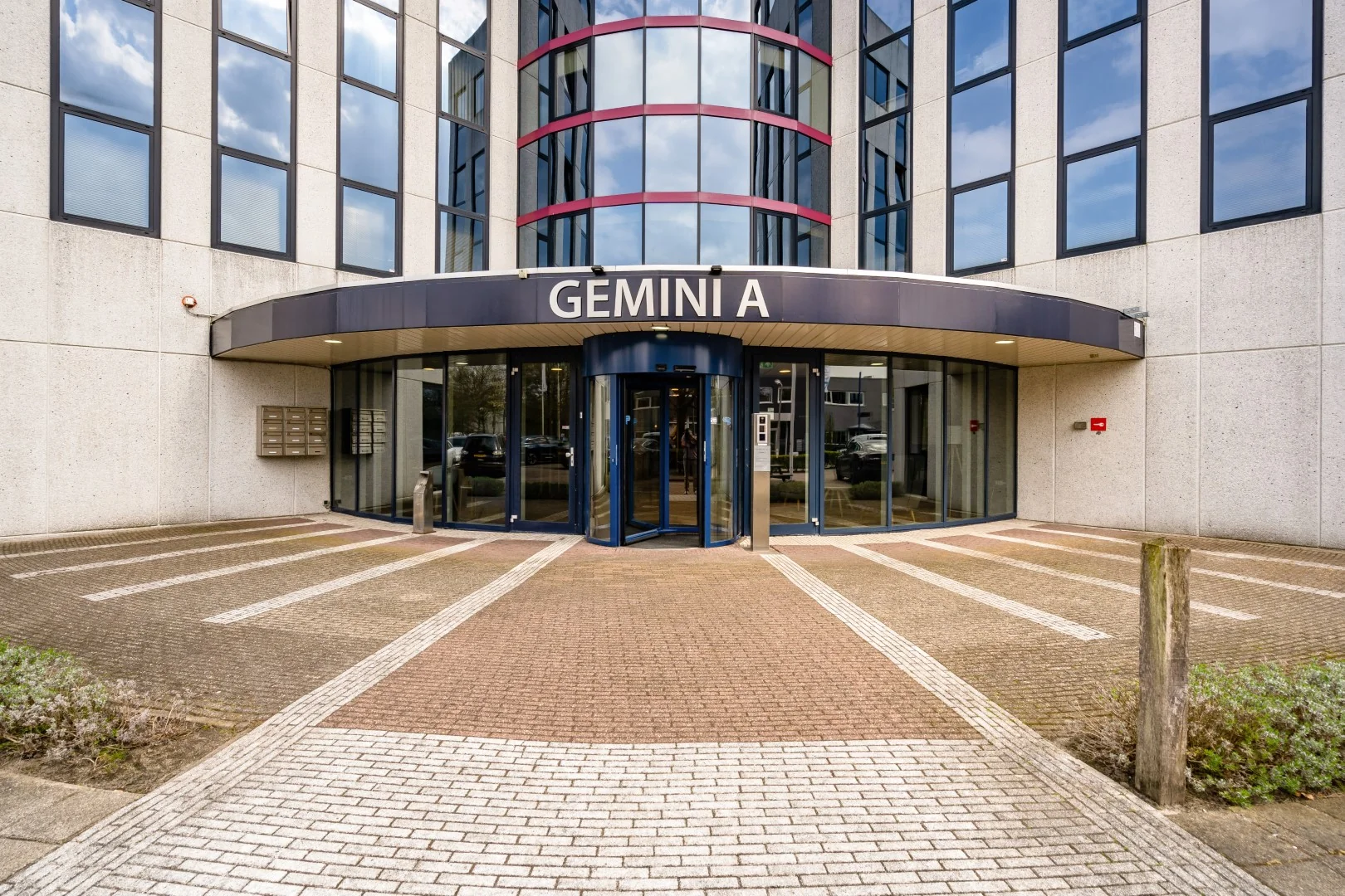 Ingang van kantoorgebouw GEMINI A aan de Printerweg, met een glazen draaideur en moderne gevel.