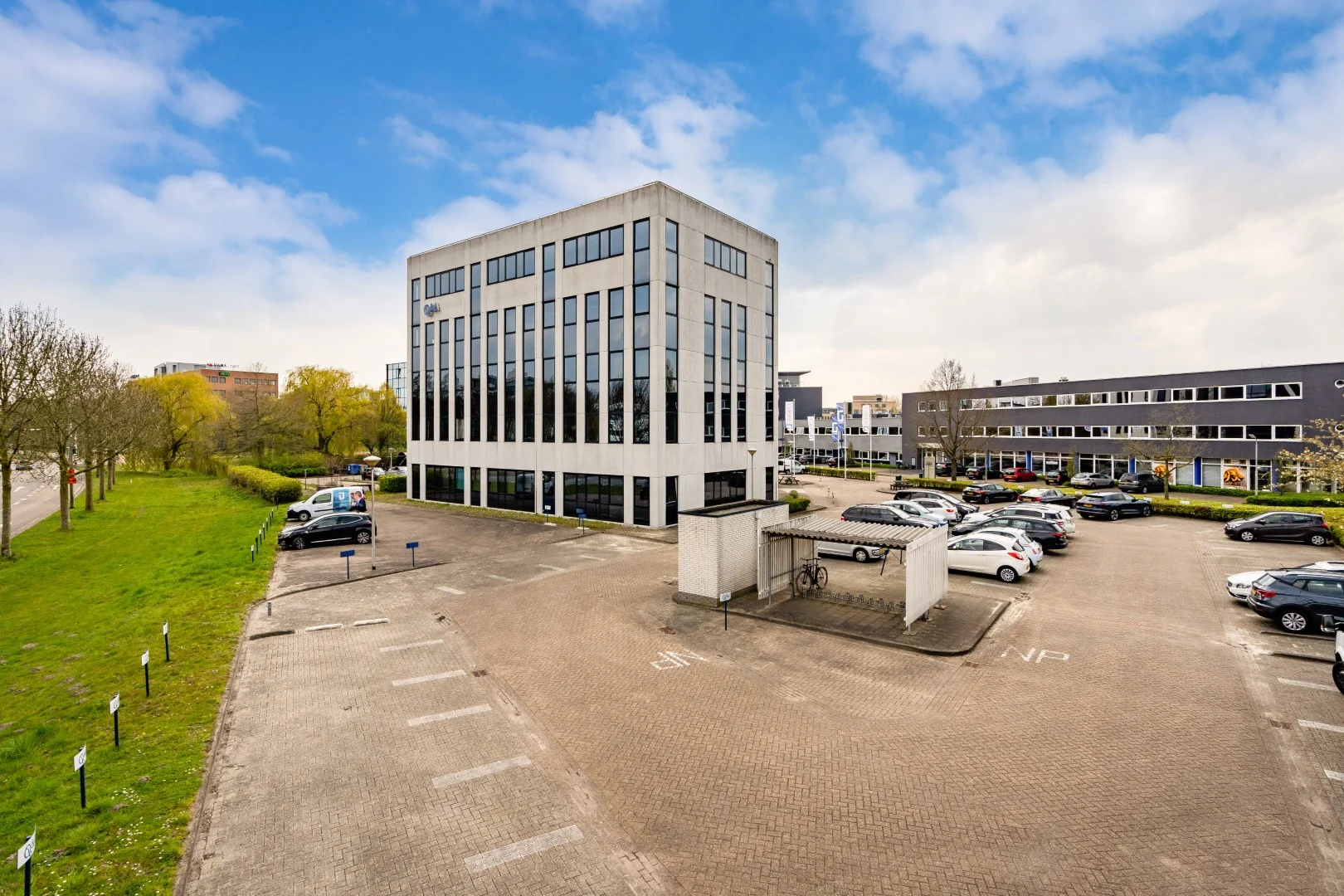 Kantoorgebouw aan de Printerweg met parkeerterrein en fietsenstalling op de voorgrond.