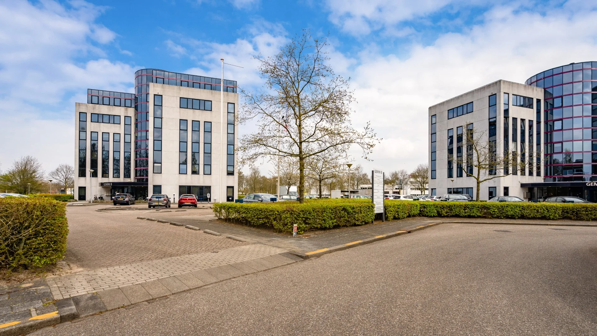 Twee moderne kantoorgebouwen aan de Printerweg met parkeerplaatsen en een centrale oprijlaan.