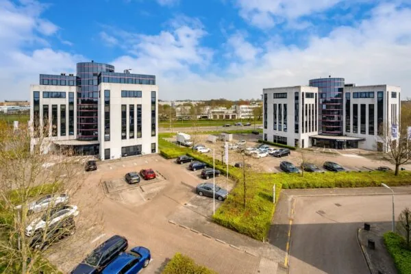 Twee moderne kantoorgebouwen aan de Printerweg met bijbehorend parkeerterrein op een zonnige dag.