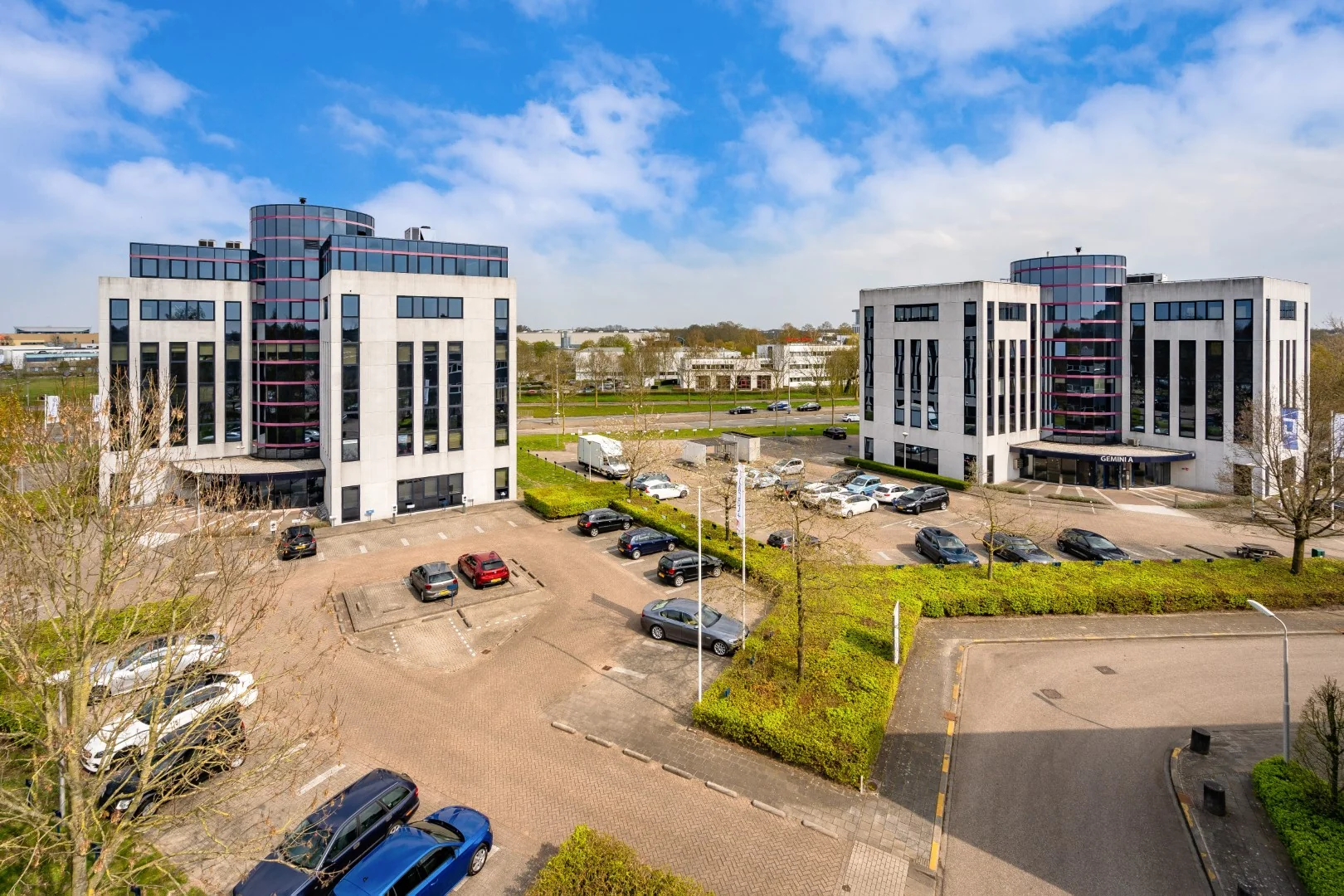 Twee moderne kantoorgebouwen aan de Printerweg met bijbehorend parkeerterrein op een zonnige dag.