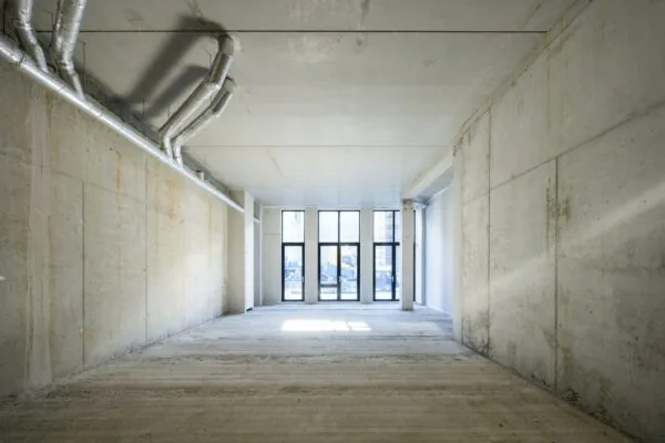 Leeg betonnen casco bedrijfsruimte aan de Oostenburgermiddenstraat met grote ramen aan de straatzijde.