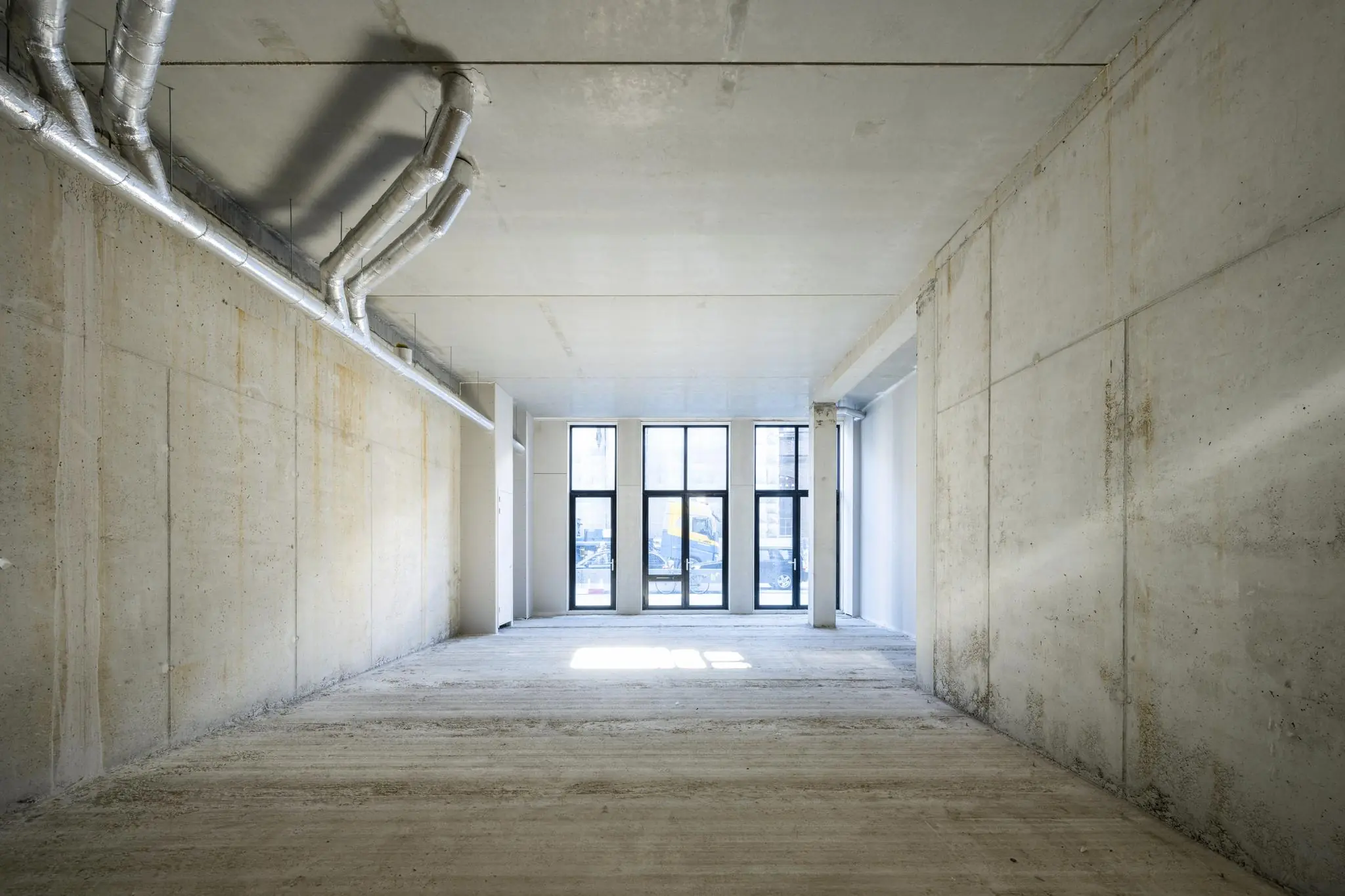 Leeg betonnen casco bedrijfsruimte aan de Oostenburgermiddenstraat met grote ramen aan de straatzijde.
