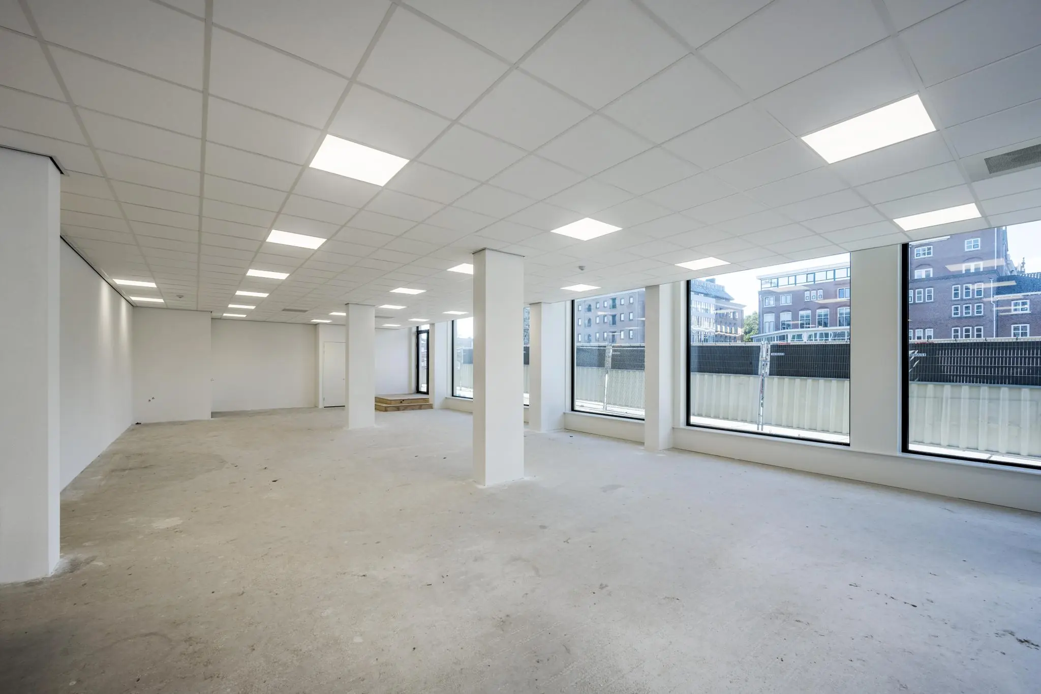 Leeg kantoorpand aan de Oostenburger Middenstraat met grote ramen en systeemplafond.
