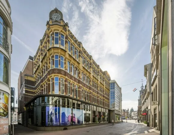 Historisch hoekpand aan het Rokin in Amsterdam met opvallende klokgevel en moderne etalage op de begane grond.