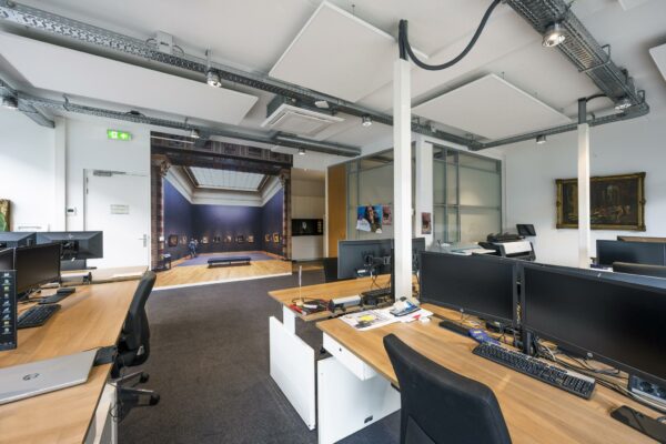 Modern kantoor met bureaus, computers en een opvallende fotowand van een kunstgalerie aan de Asterweg.