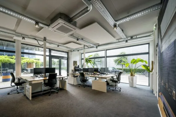 Modern kantoorinterieur aan de Asterweg met meerdere werkplekken, grote ramen en veel daglicht.