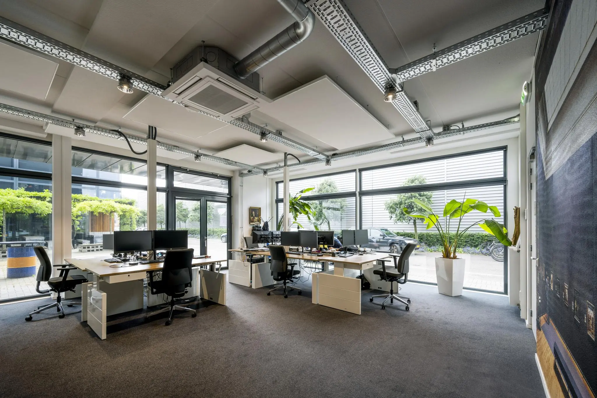 Modern kantoorinterieur aan de Asterweg met meerdere werkplekken, grote ramen en veel daglicht.