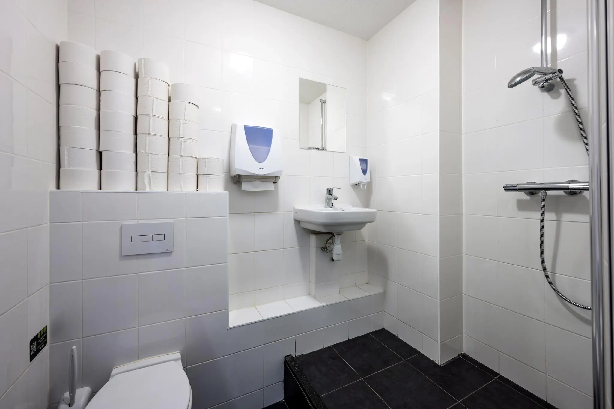 Badkamer met douche, toilet, wastafel en meerdere stapels toiletpapier aan de Asterweg.