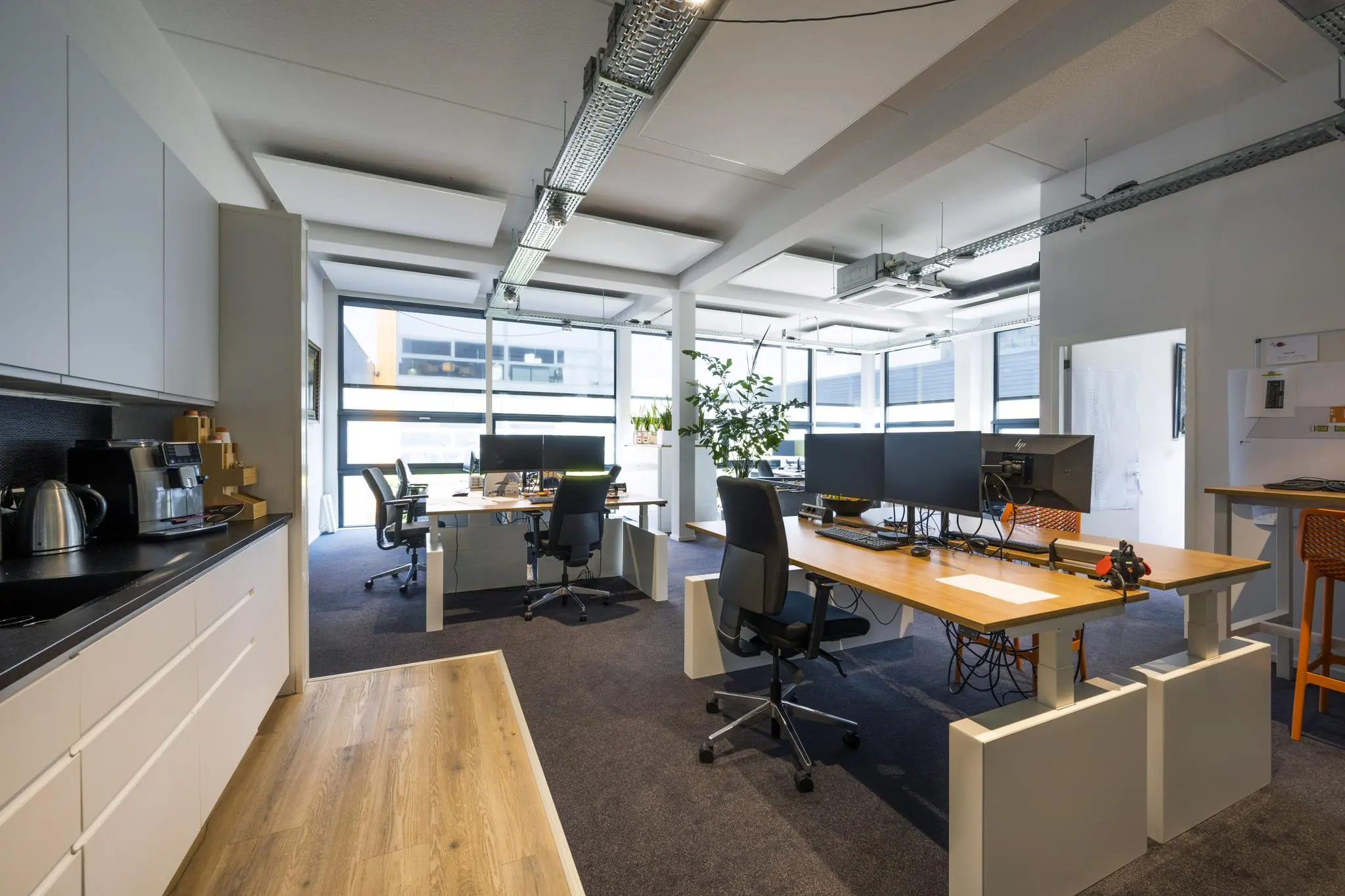 Modern kantoorinterieur aan de Asterweg met werkplekken, bureaus en een koffiehoek.