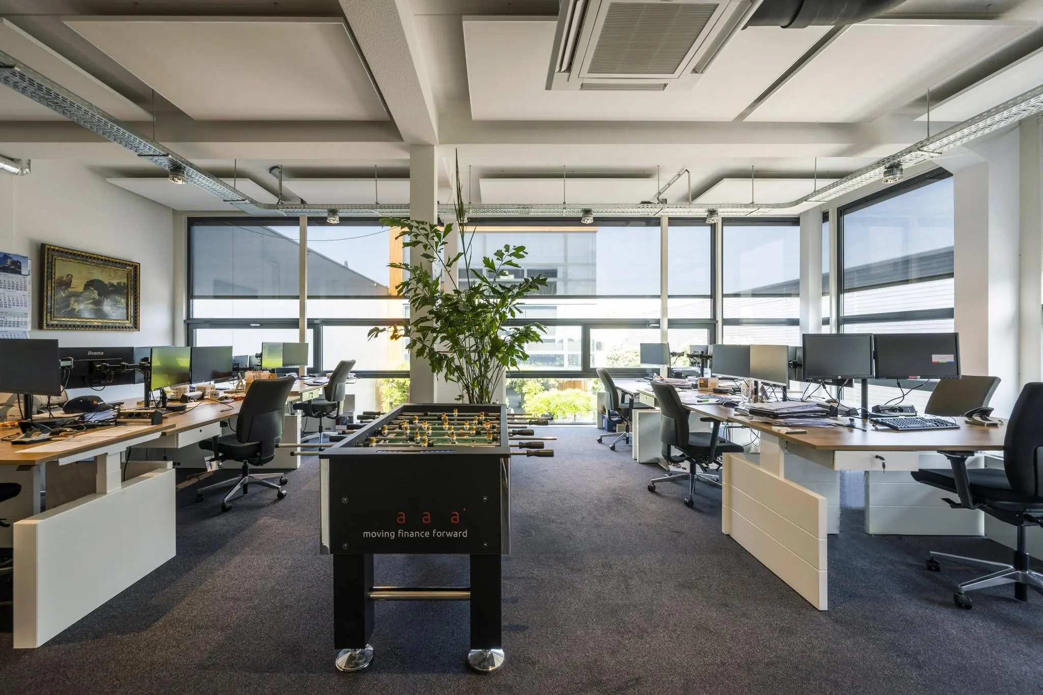 Modern kantoorinterieur aan de Asterweg met bureaus, computers, een tafelvoetbaltafel en veel daglicht.