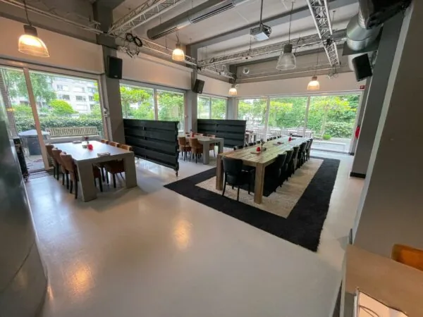 Moderne vergaderruimte aan de Hengeveldstraat met grote houten tafels, veel daglicht en uitzicht op een groene binnentuin.