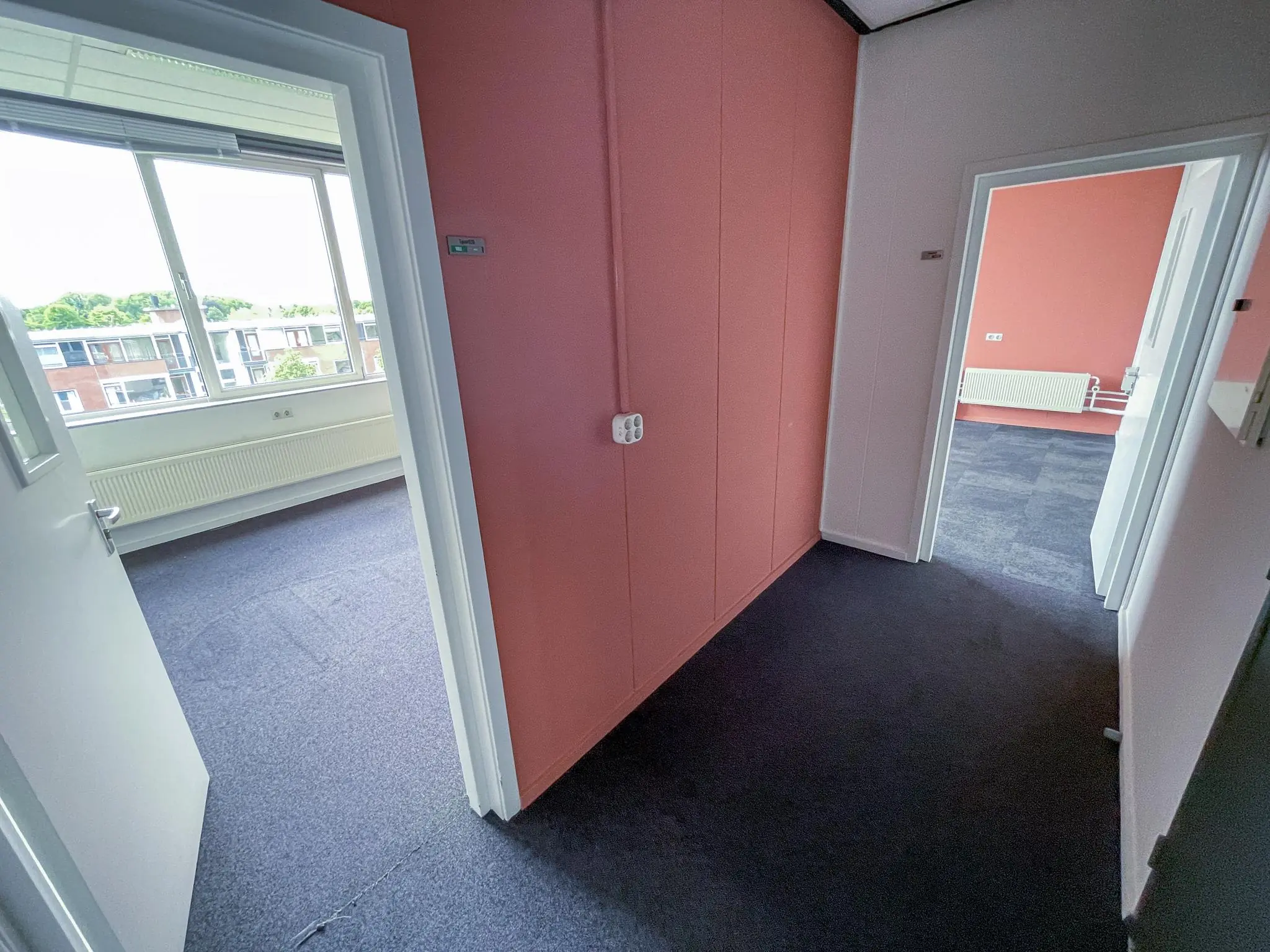 Gang in een kantoorpand aan de Hengeveldstraat met open deuren naar twee ruime, lichtovergoten kamers.