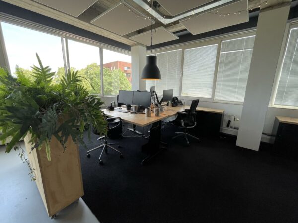 Modern kantoor aan de Hengeveldstraat met werkplekken, computers en grote ramen met uitzicht op groen.