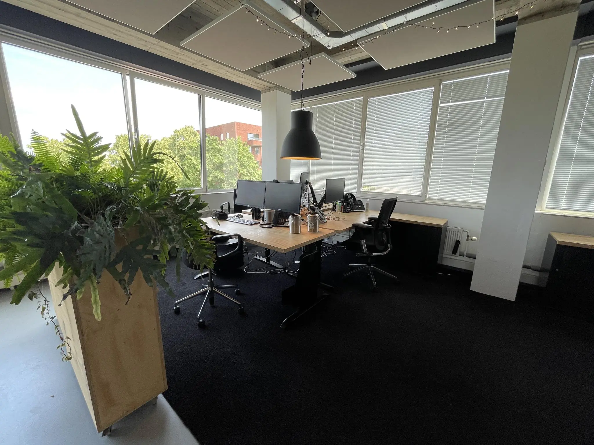 Modern kantoor aan de Hengeveldstraat met werkplekken, computers en grote ramen met uitzicht op groen.