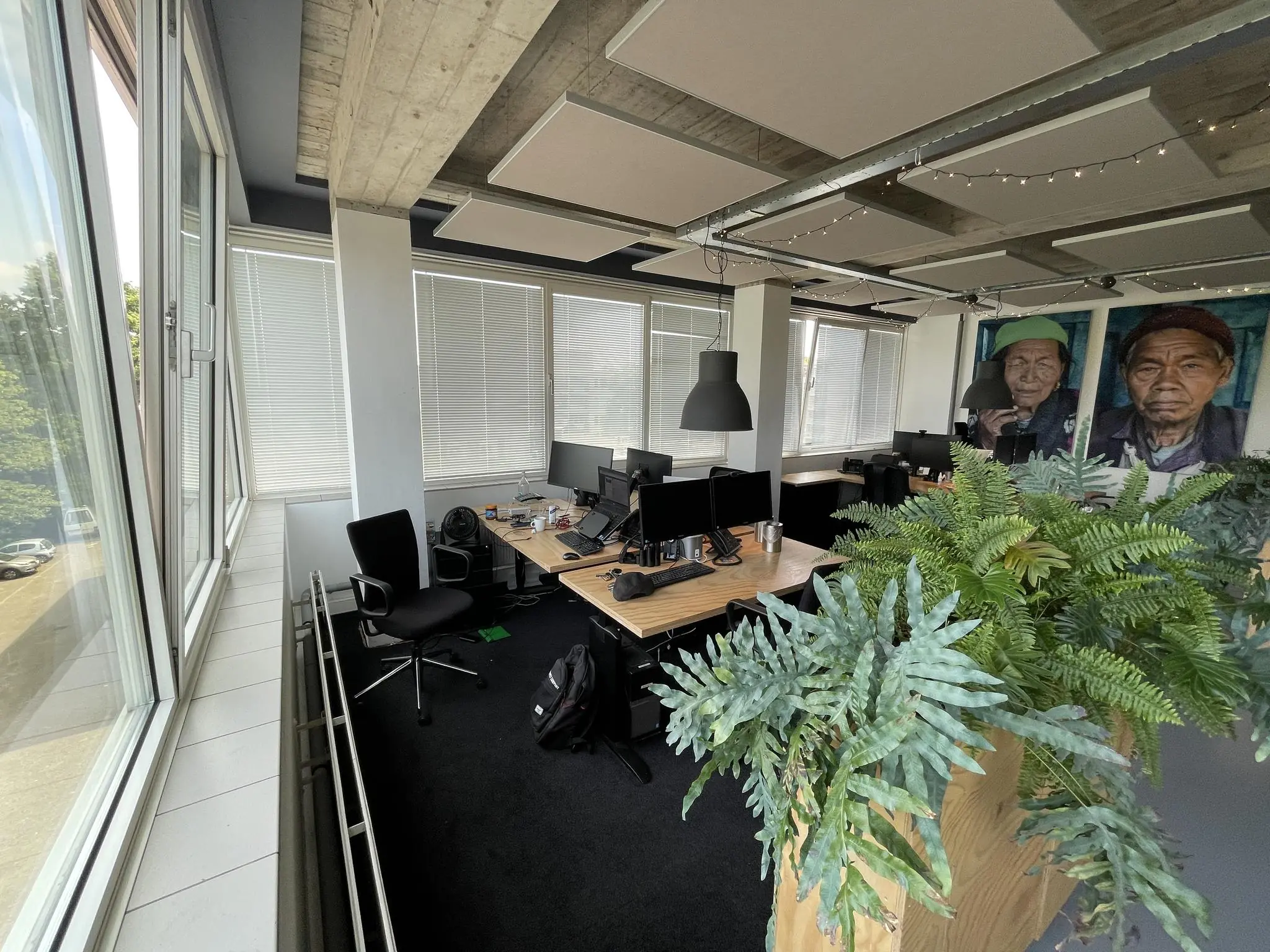 Moderne kantoorruimte aan de Hengeveldstraat met werkplekken, grote ramen, planten en portretschilderijen aan de muur.