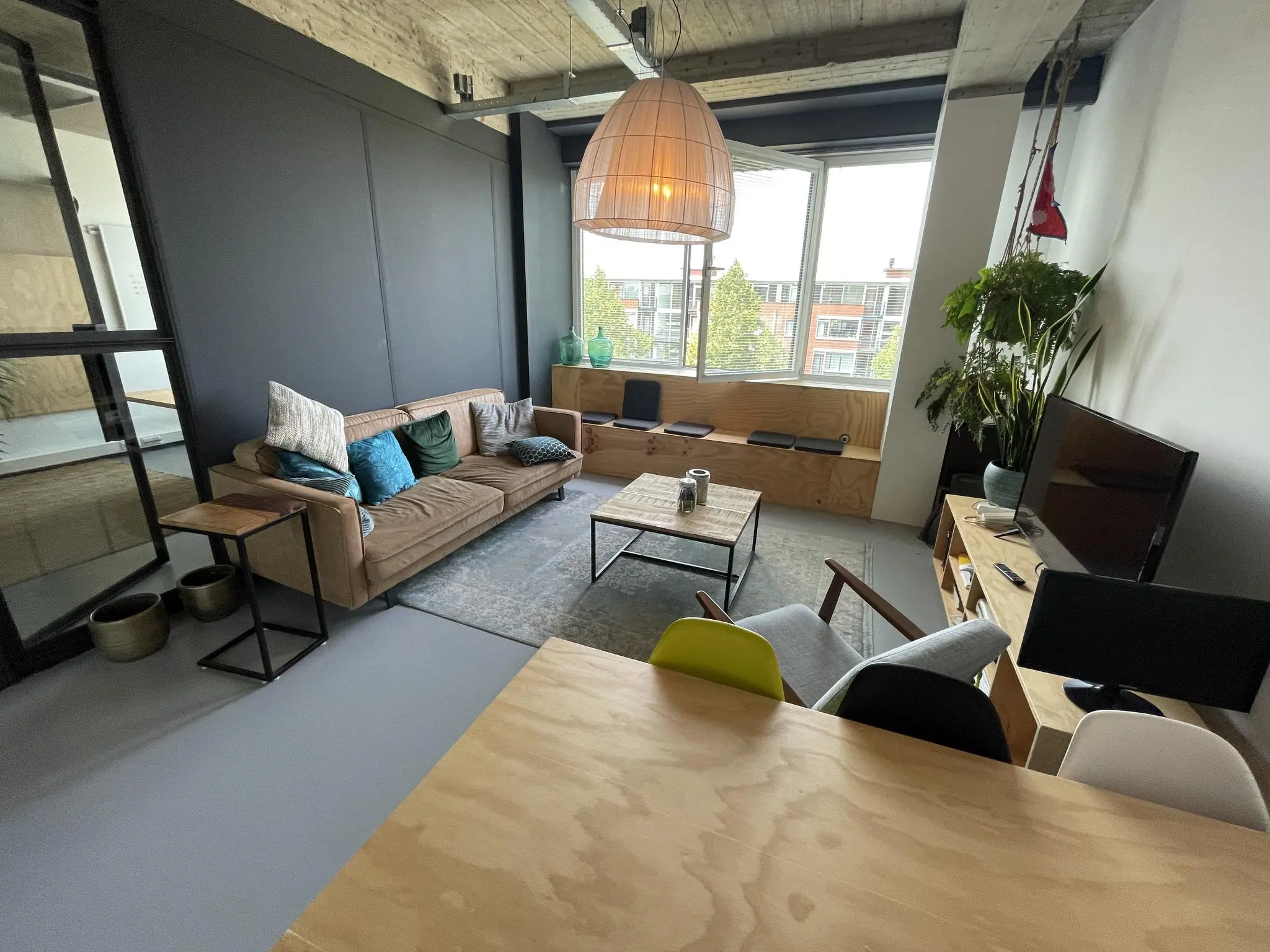 Modern ingerichte woonkamer aan de Hengeveldstraat met een zithoek, houten meubels en grote raampartij.