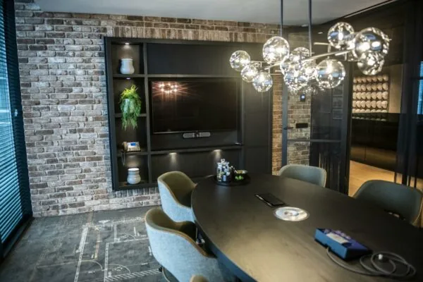 Moderne vergaderruimte in Stationspark met ovale tafel, designverlichting en bakstenen muur.