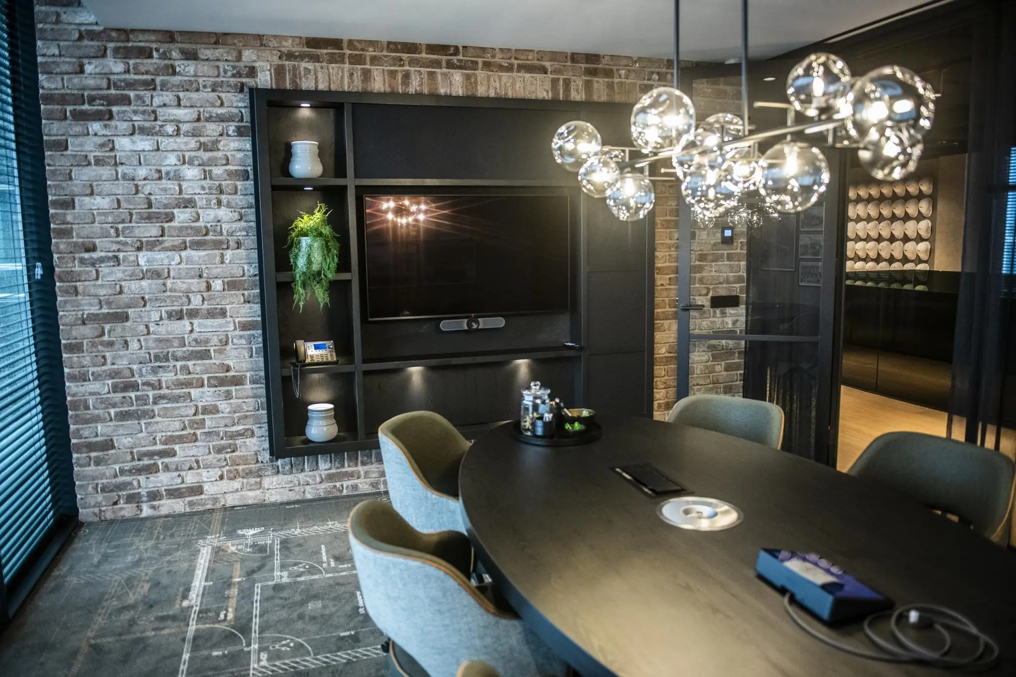 Moderne vergaderruimte in Stationspark met ovale tafel, designverlichting en bakstenen muur.