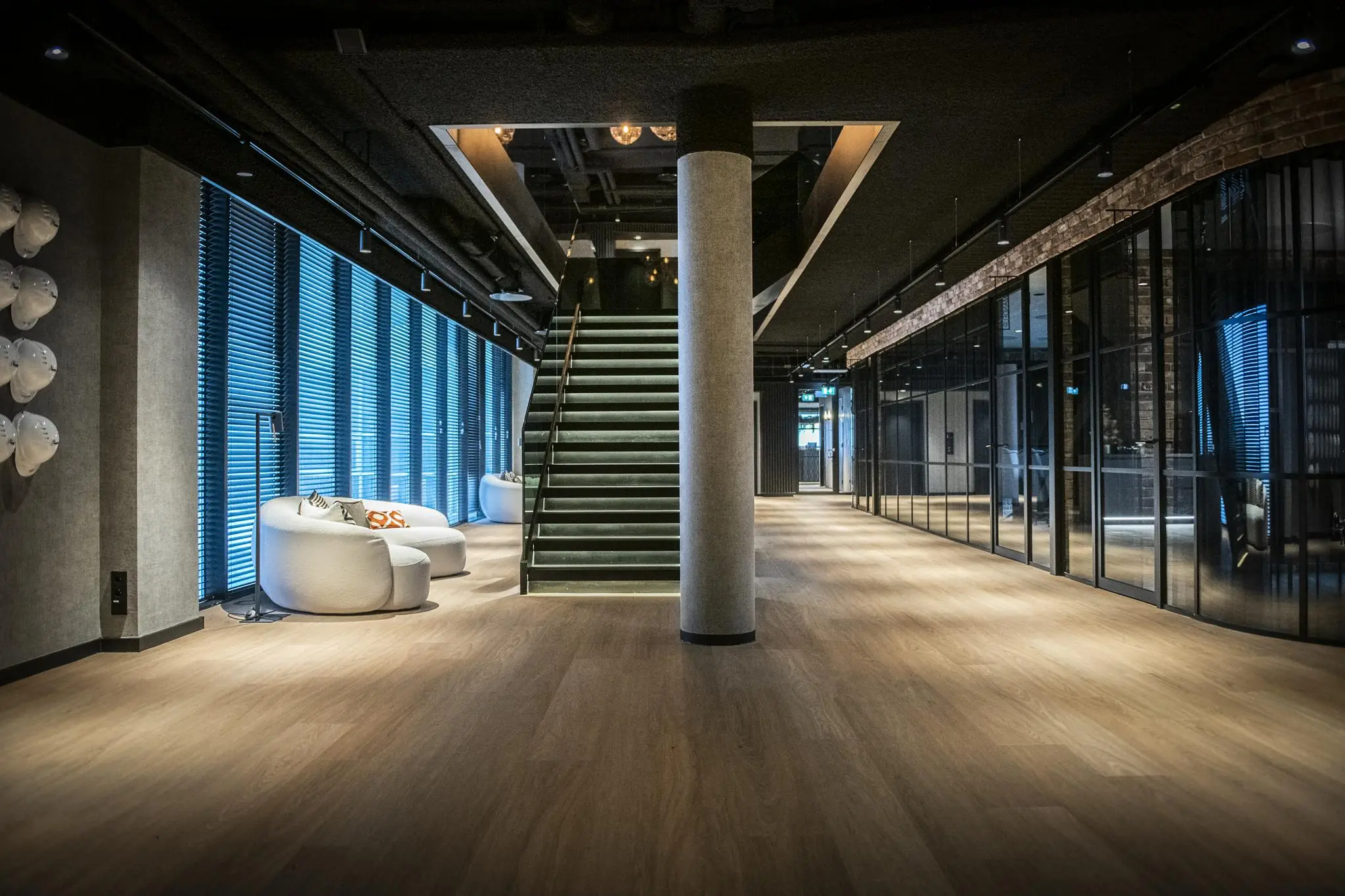 Modern interieur van een kantoorpand aan het Stationspark met een centrale trap, houten vloer en glazen wanden.