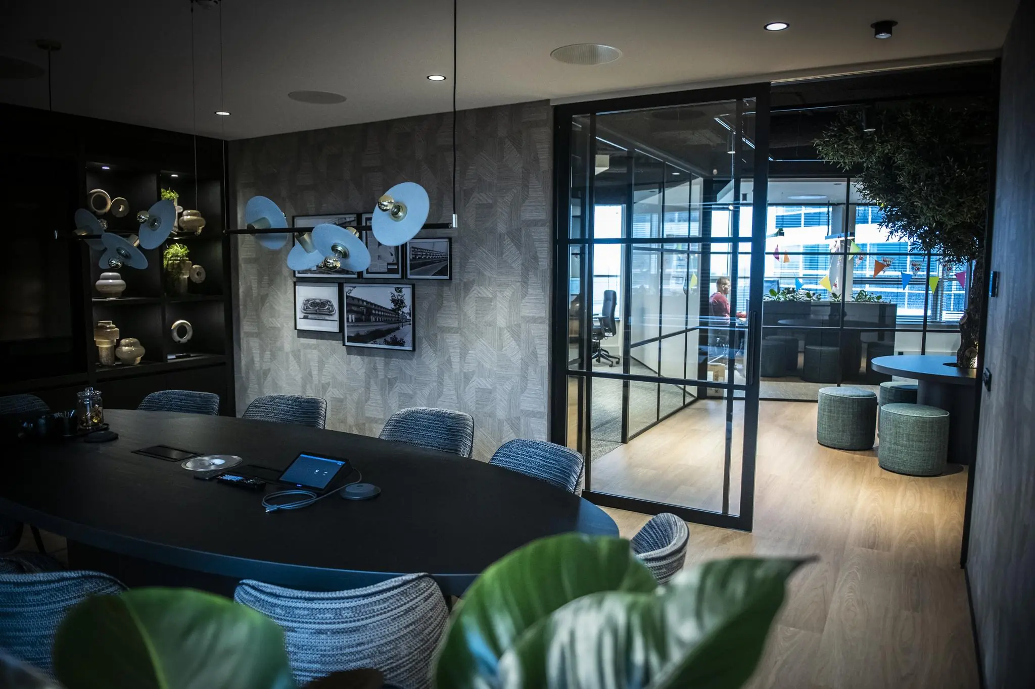 Moderne vergaderruimte bij Stationspark met glazen wanden, stijlvolle inrichting en zicht op aangrenzend kantoor.