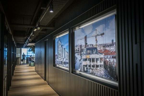 Moderne kantoorhal met houten vloer en grote foto's van het Stationspark-project aan de muur.