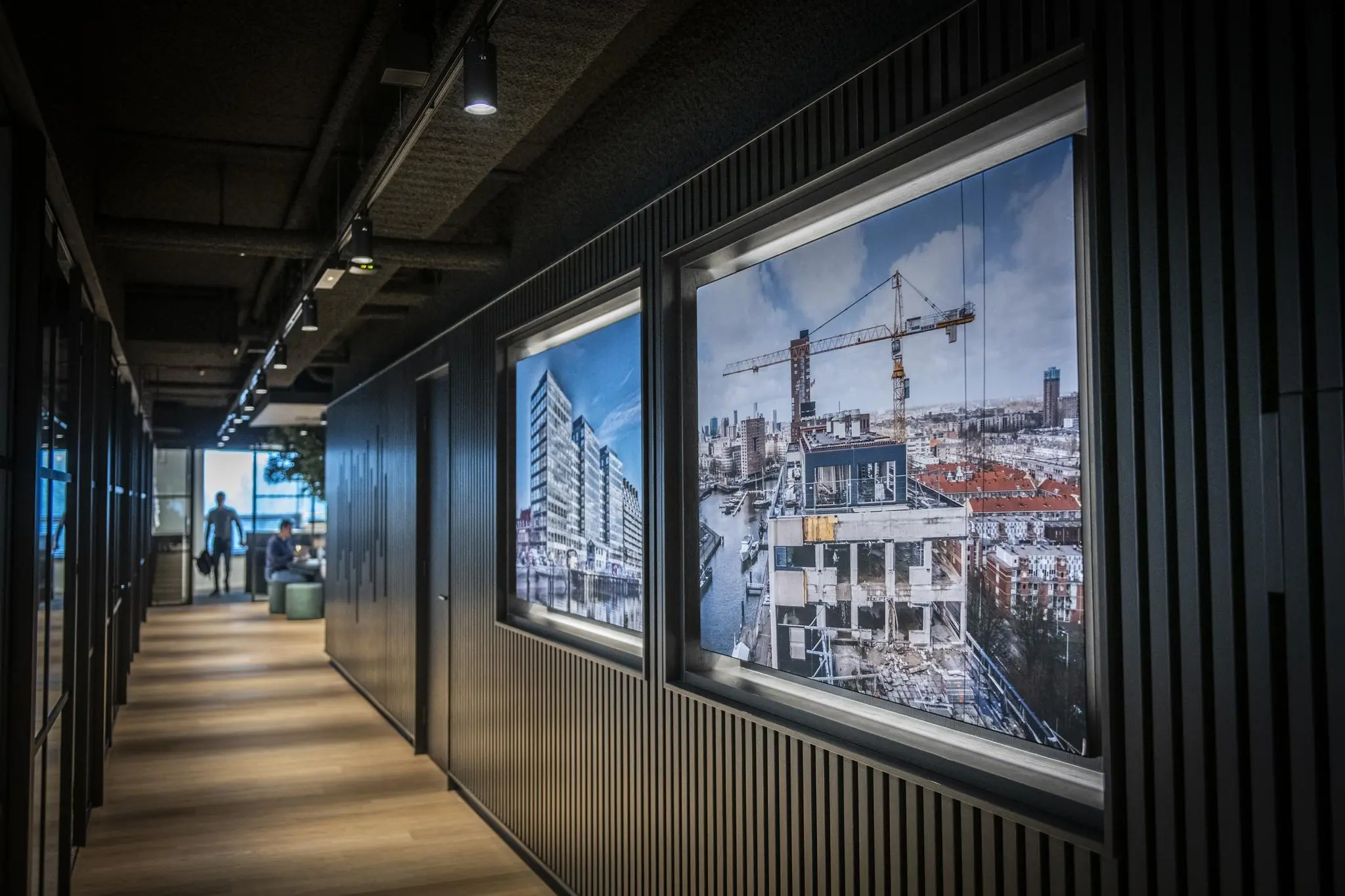 Moderne kantoorhal met houten vloer en grote foto's van het Stationspark-project aan de muur.