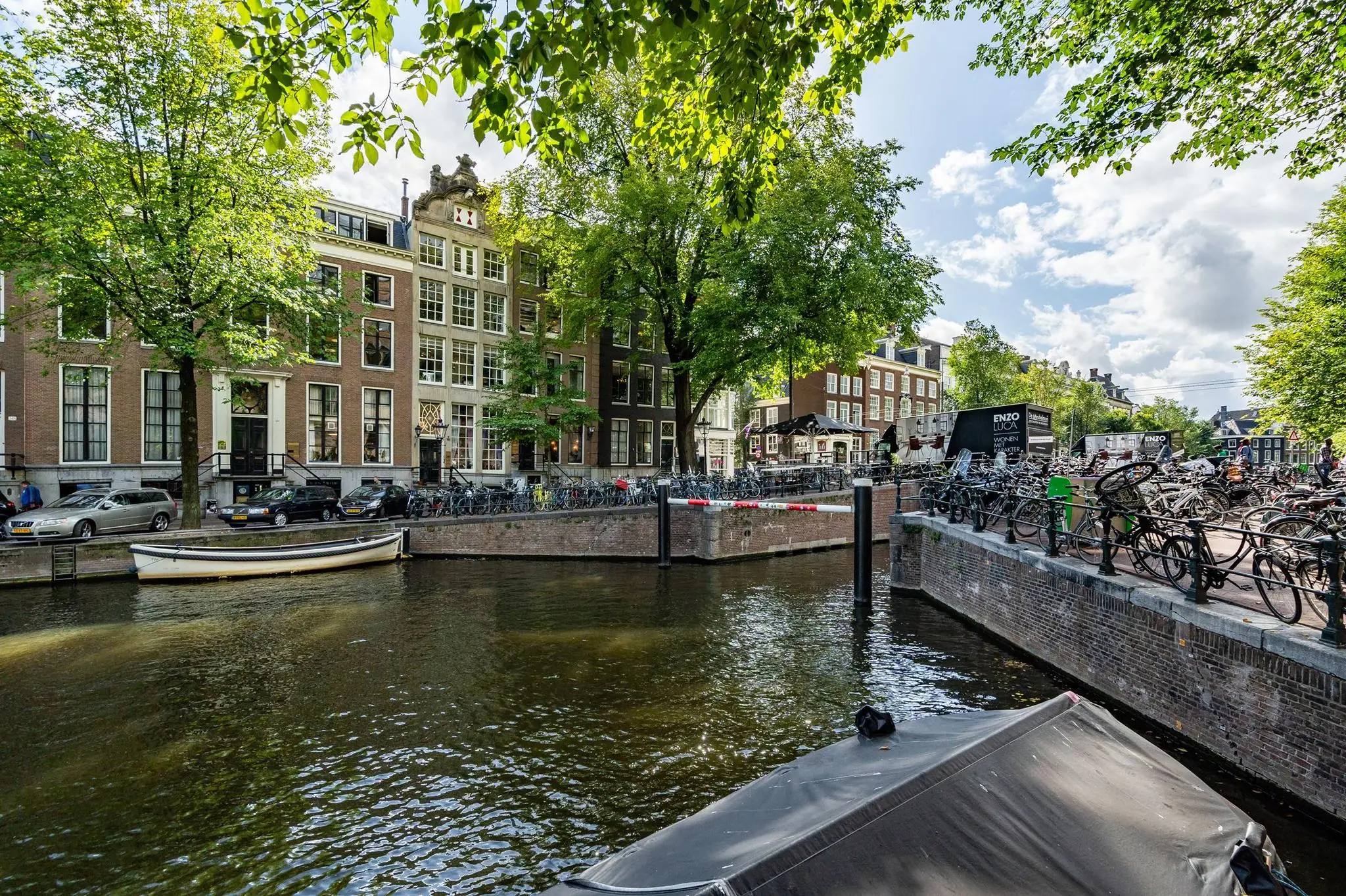 Uitzicht op de Herengracht in Amsterdam met historische grachtenpanden, fietsen en een aangemeerde boot.