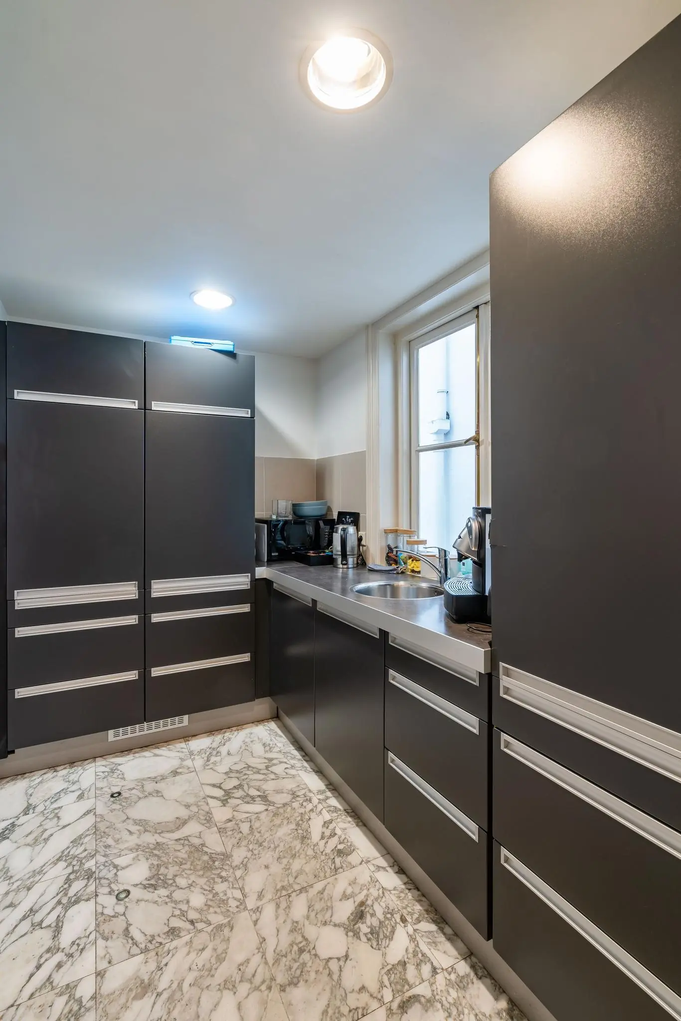 Moderne keuken met donkere kasten, rvs-aanrecht en marmeren vloer aan de Herengracht.