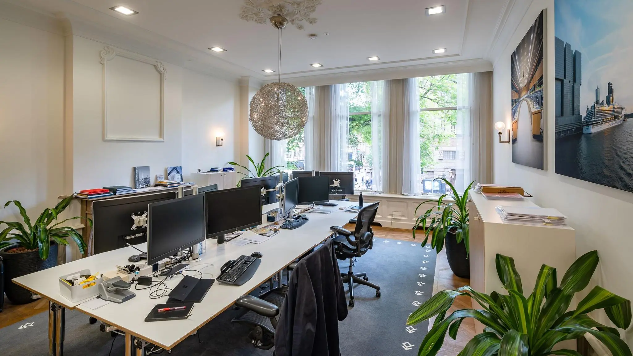 Modern kantoor aan de Herengracht met werkplekken, grote ramen, planten en stadszicht.
