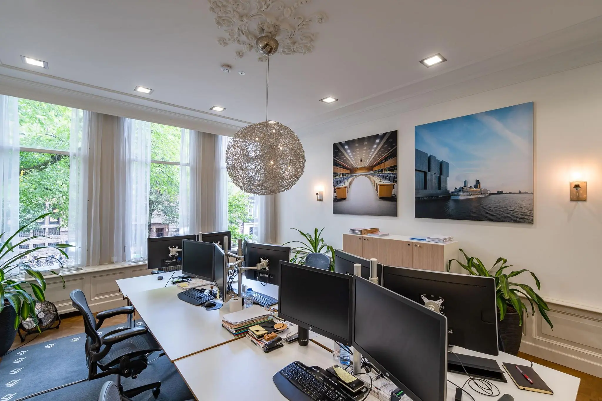 Modern kantoor aan de Herengracht met meerdere werkplekken, grote ramen en foto’s van Amsterdam aan de muur.