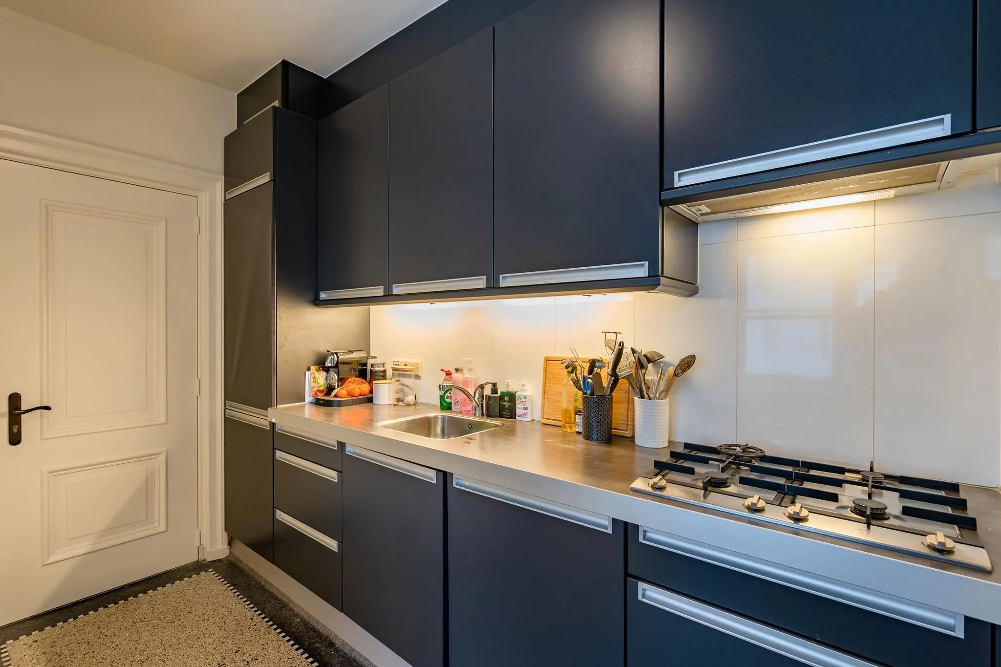 Moderne keuken aan de Herengracht met donkerblauwe kasten, gaskookplaat en ingebouwde verlichting.