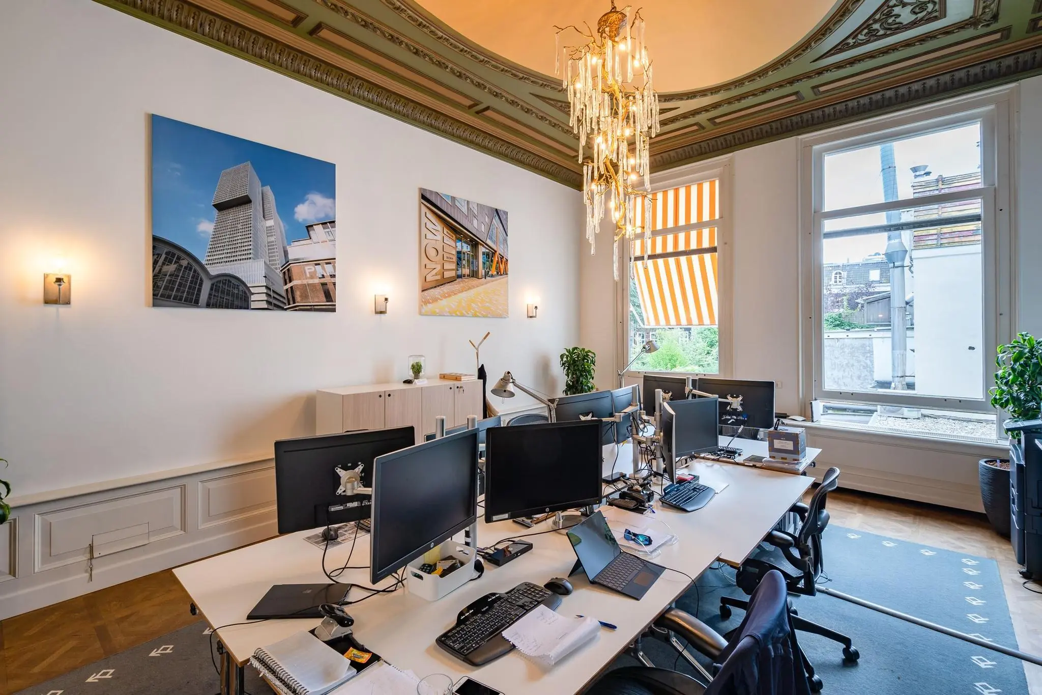 Stijlvol ingericht kantoor aan de Herengracht met moderne werkplekken, klassieke ornamenten en grote ramen met zonwering.