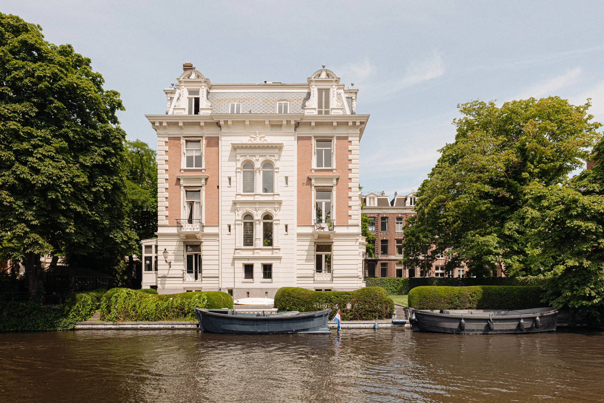 Statig herenhuis aan de Weteringschans in Amsterdam met boten aangemeerd aan de gracht.