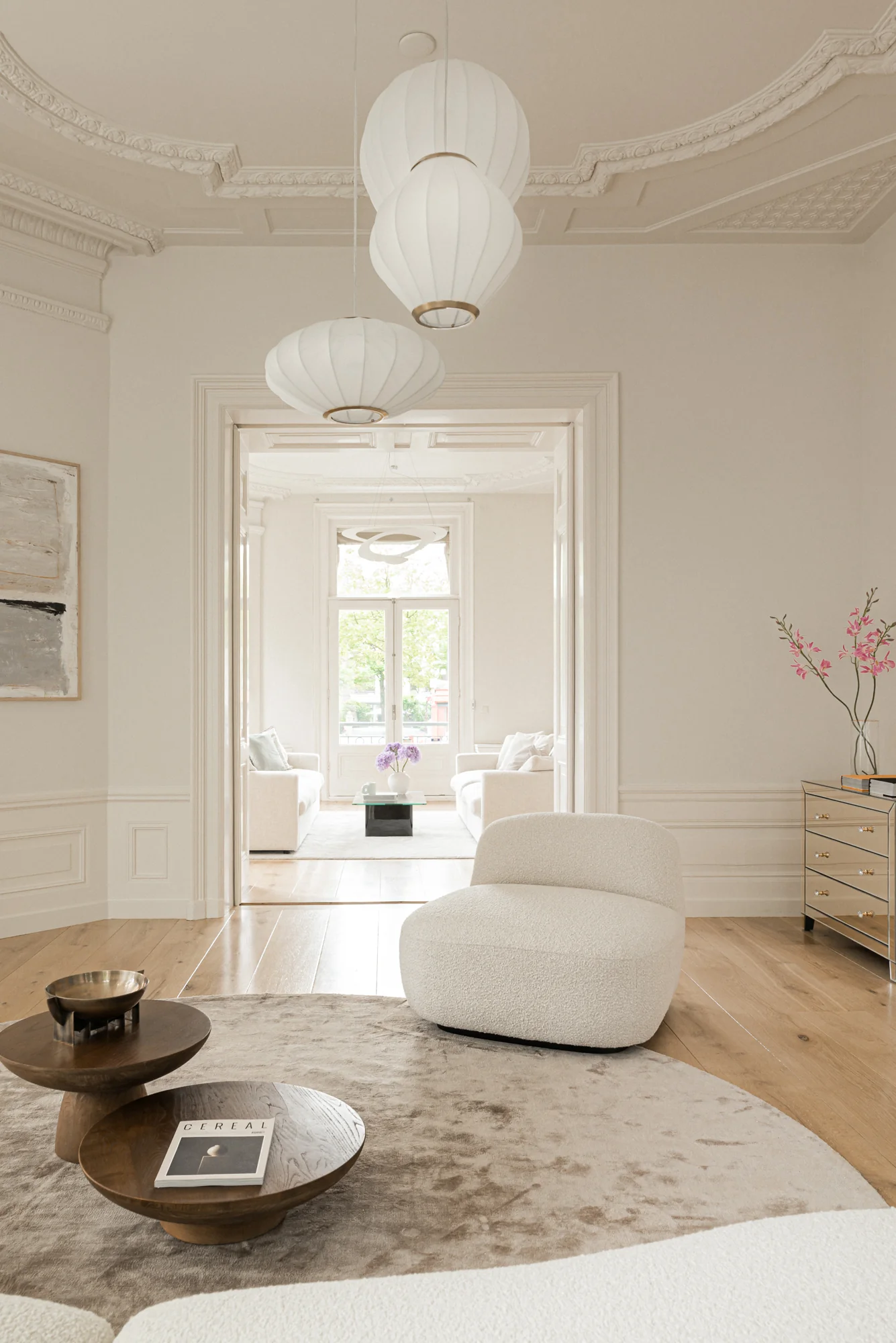 Stijlvol ingerichte woonkamer aan de Weteringschans met zacht beige interieur, moderne meubels en klassiek ornamentenplafond.