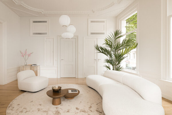 Licht en modern interieur aan de Weteringschans met witte designmeubels, houten vloer en grote ramen.