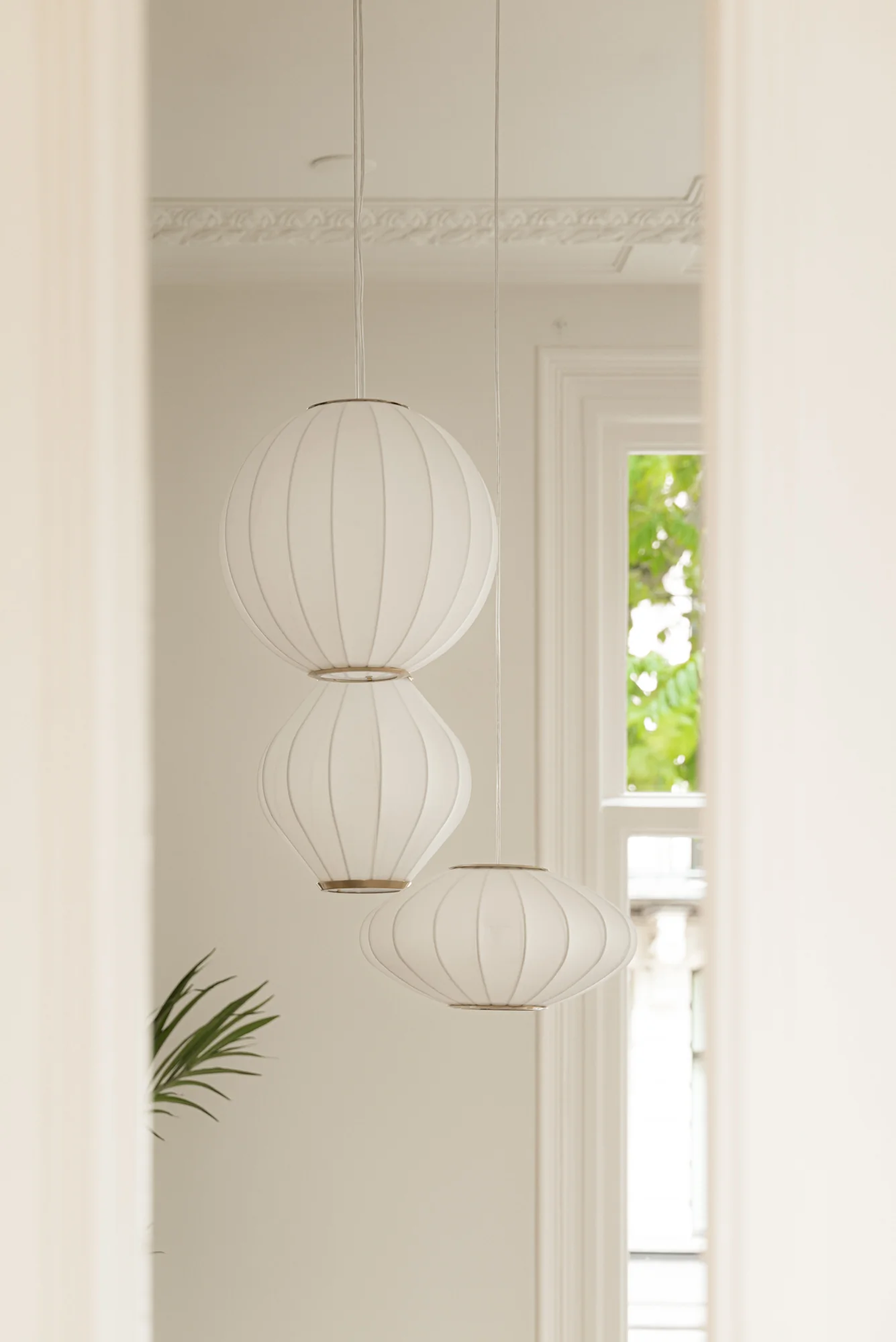 Drie witte, moderne hanglampen in een licht interieur aan de Weteringschans.