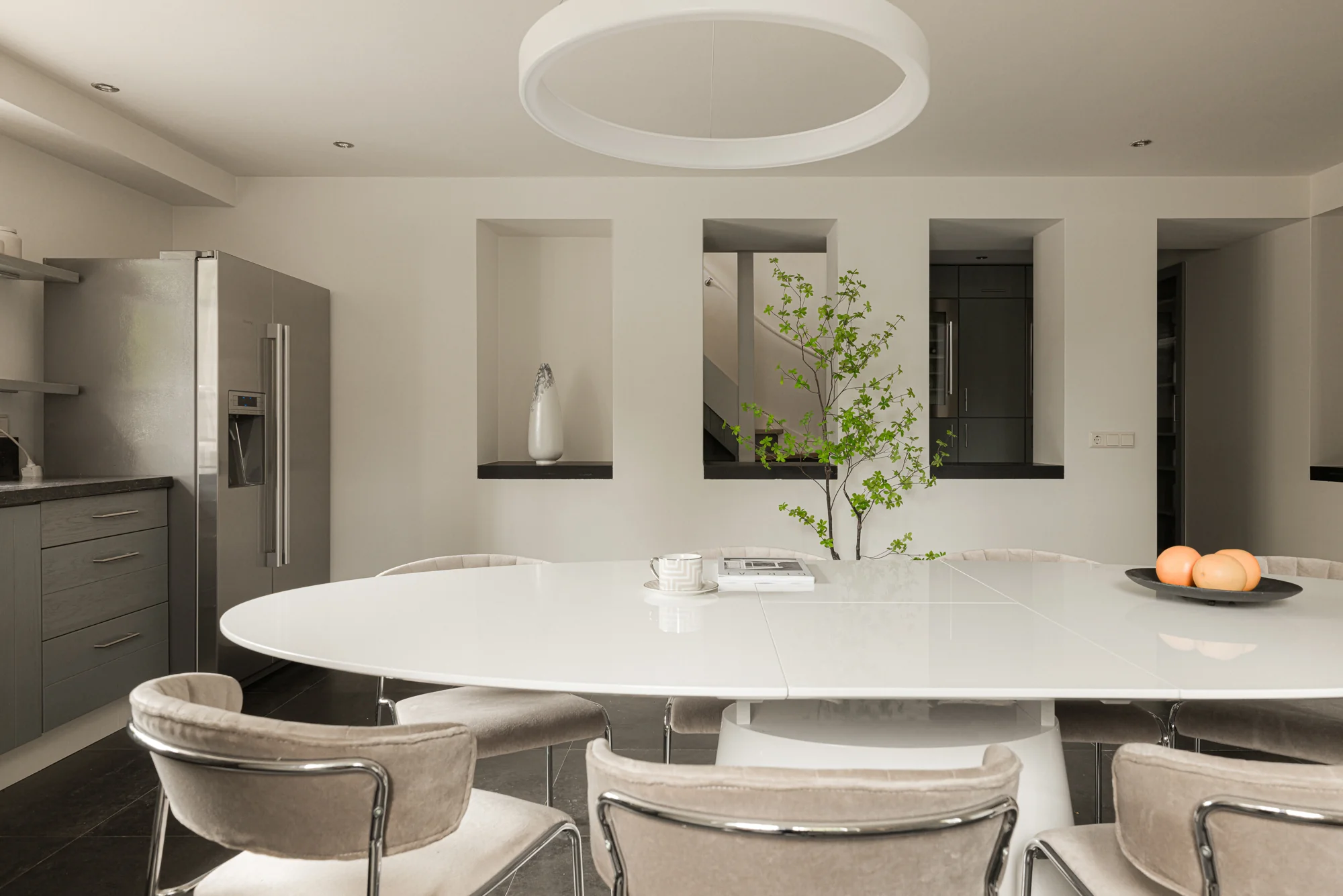Moderne eetkeuken aan de Weteringschans met minimalistisch interieur, witte ovale eettafel en roestvrijstalen koelkast.