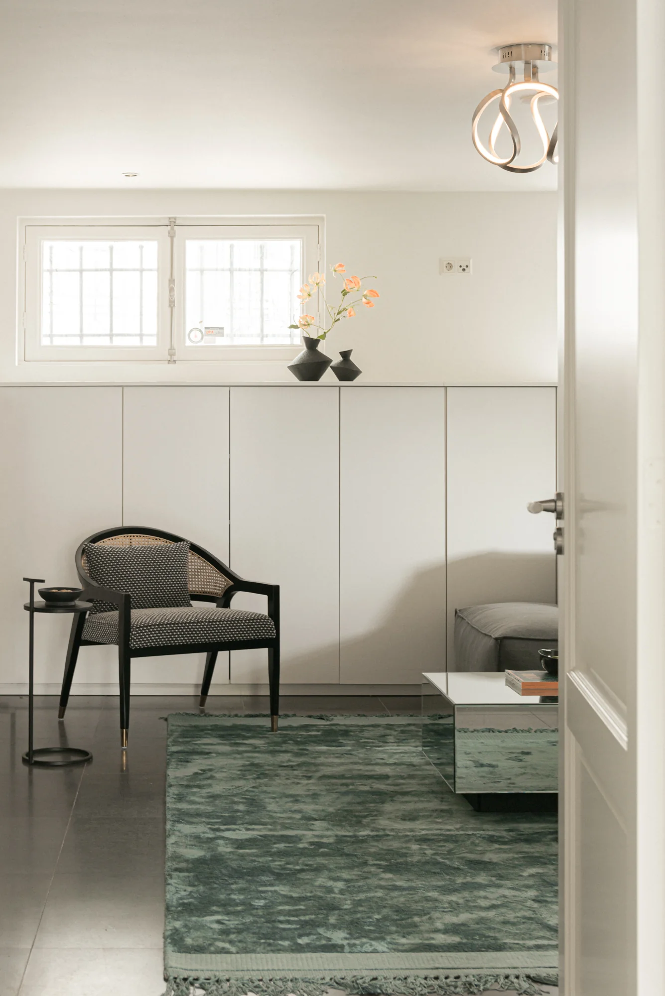 Modern ingerichte zitruimte aan de Weteringschans met designstoel, groen vloerkleed en minimalistische decoratie.