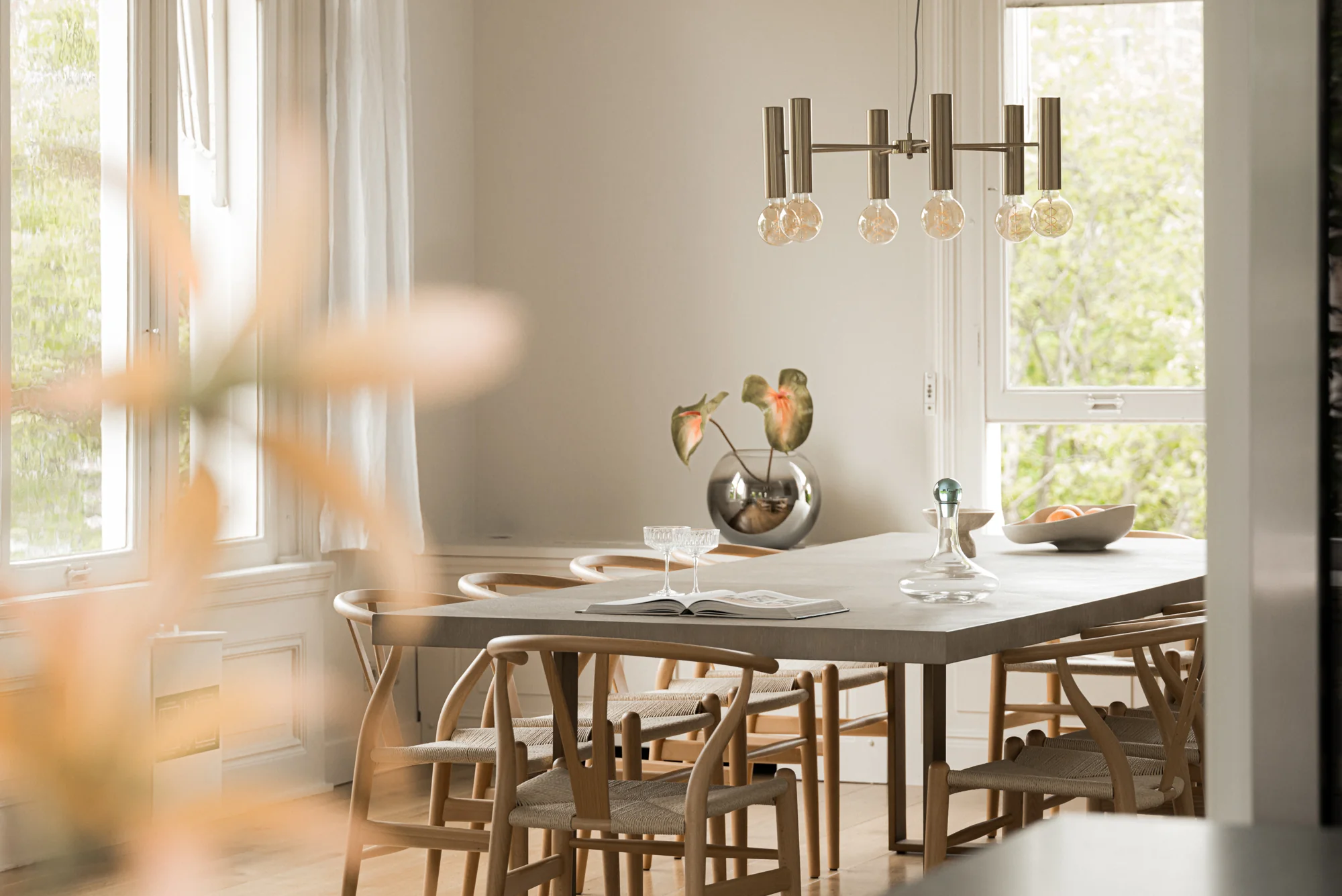 Stijlvol ingerichte eetkamer aan de Weteringschans met houten stoelen, moderne verlichting en een grote betonnen eettafel.