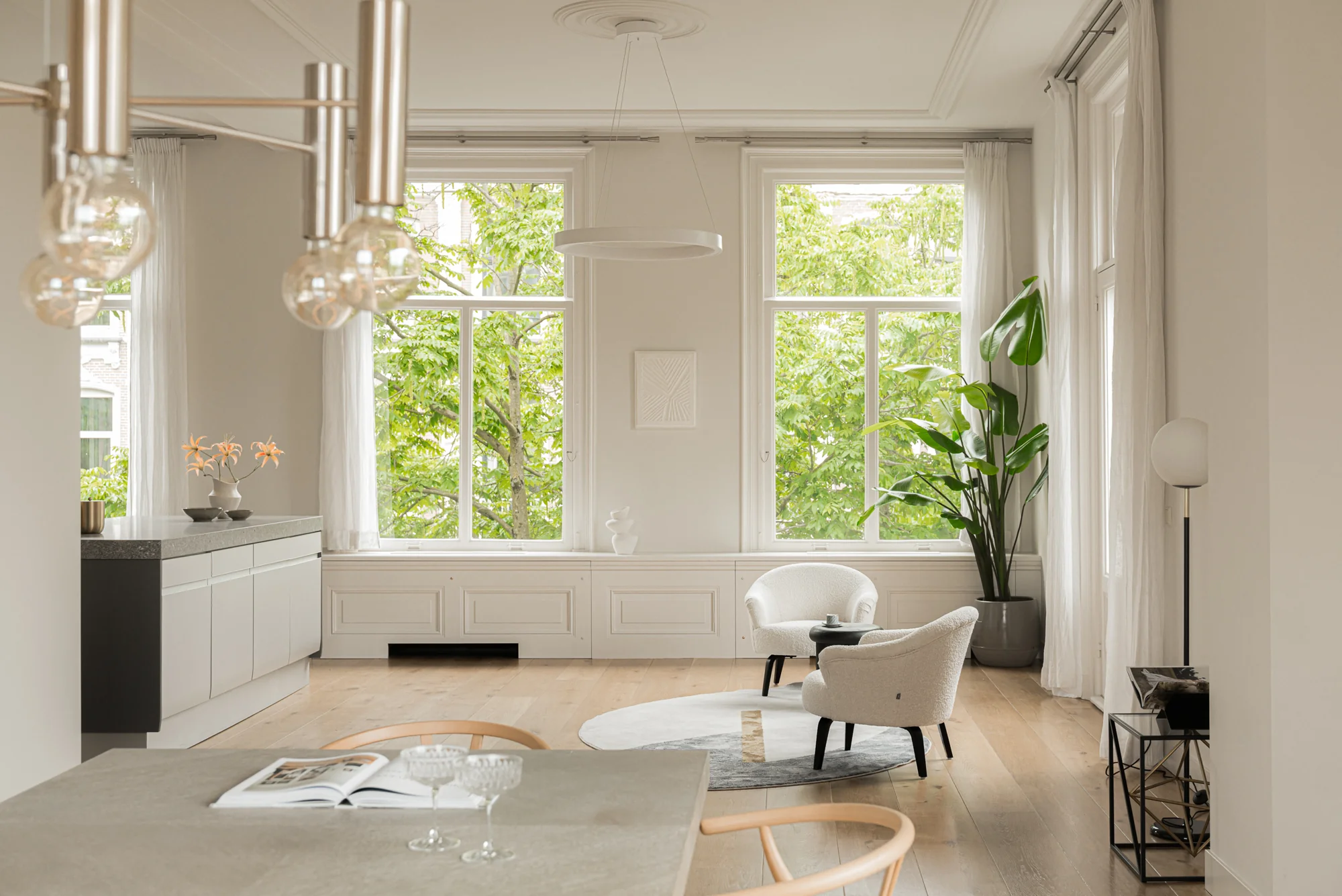 Modern en licht interieur van een appartement aan de Weteringschans, met grote ramen, minimalistische meubels en een houten vloer.