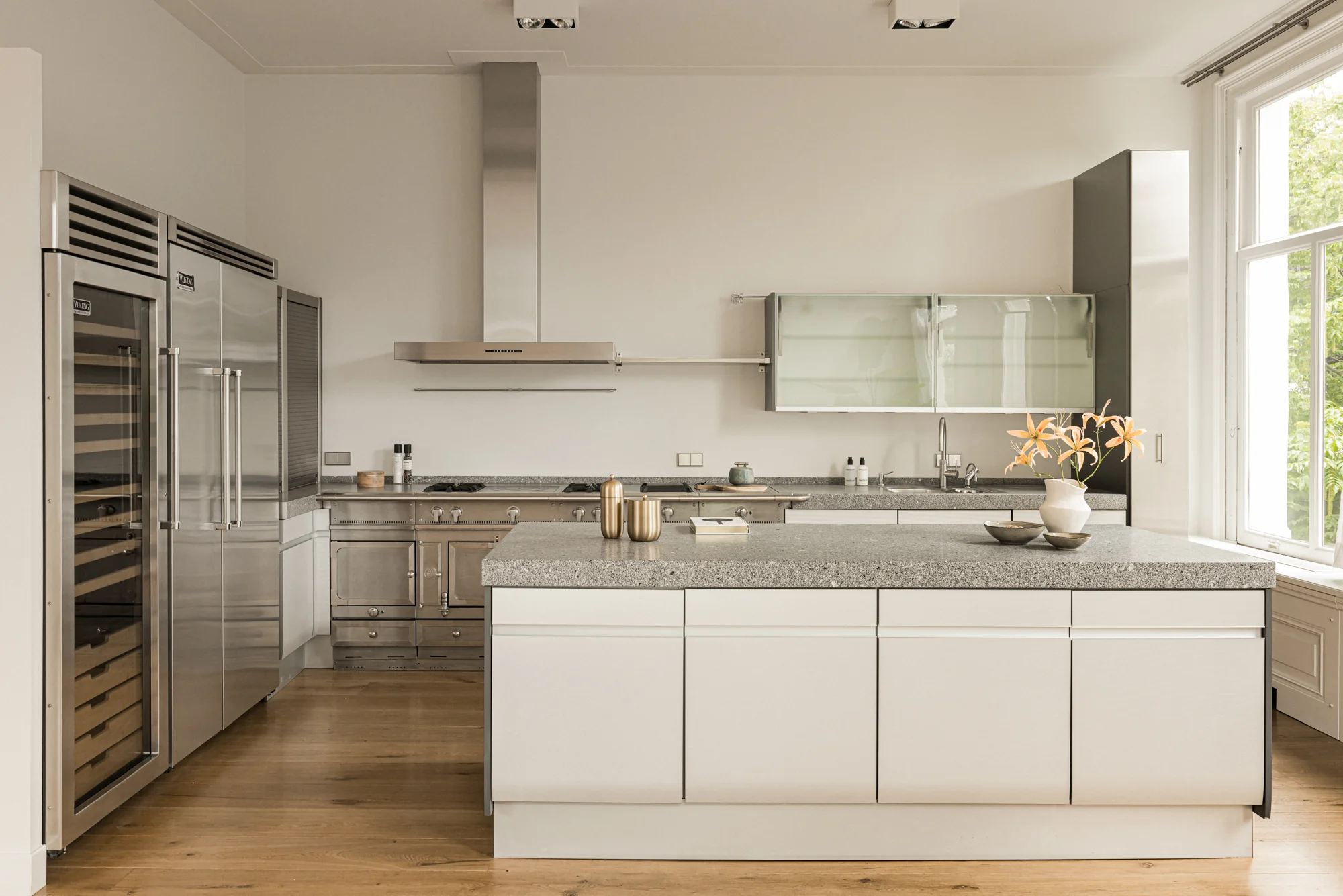 Moderne keuken aan de Weteringschans met strakke witte kasten, een kookeiland en roestvrijstalen apparaten.