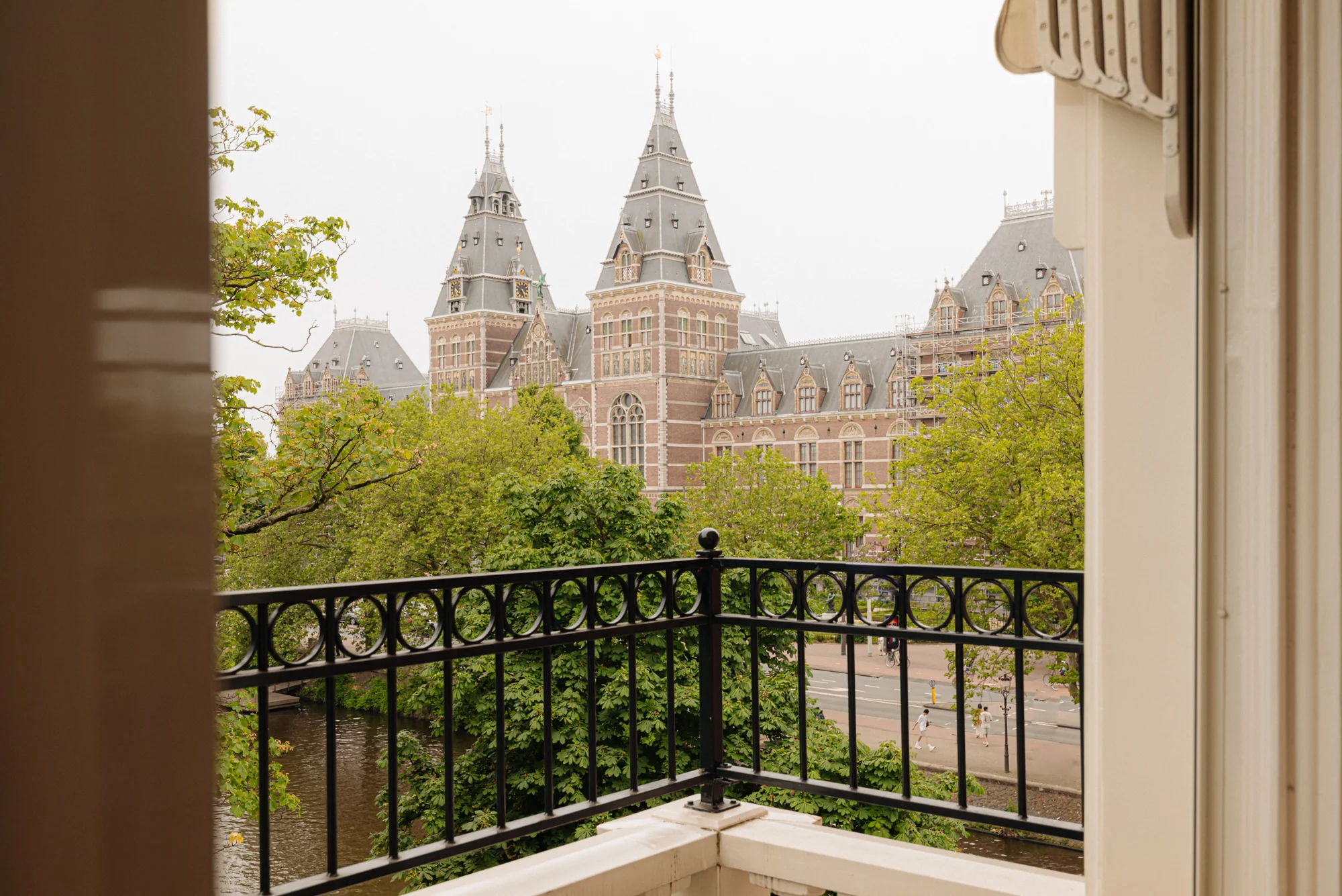 Uitzicht vanaf een balkon op het Rijksmuseum en de Weteringschans in Amsterdam tussen groene bomen.