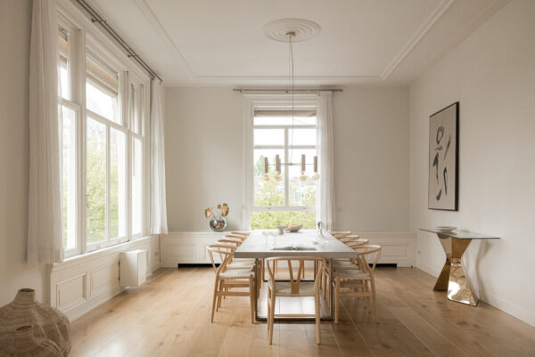 Licht en modern ingerichte eetkamer aan de Weteringschans met houten vloer, minimalistisch meubilair en grote ramen.