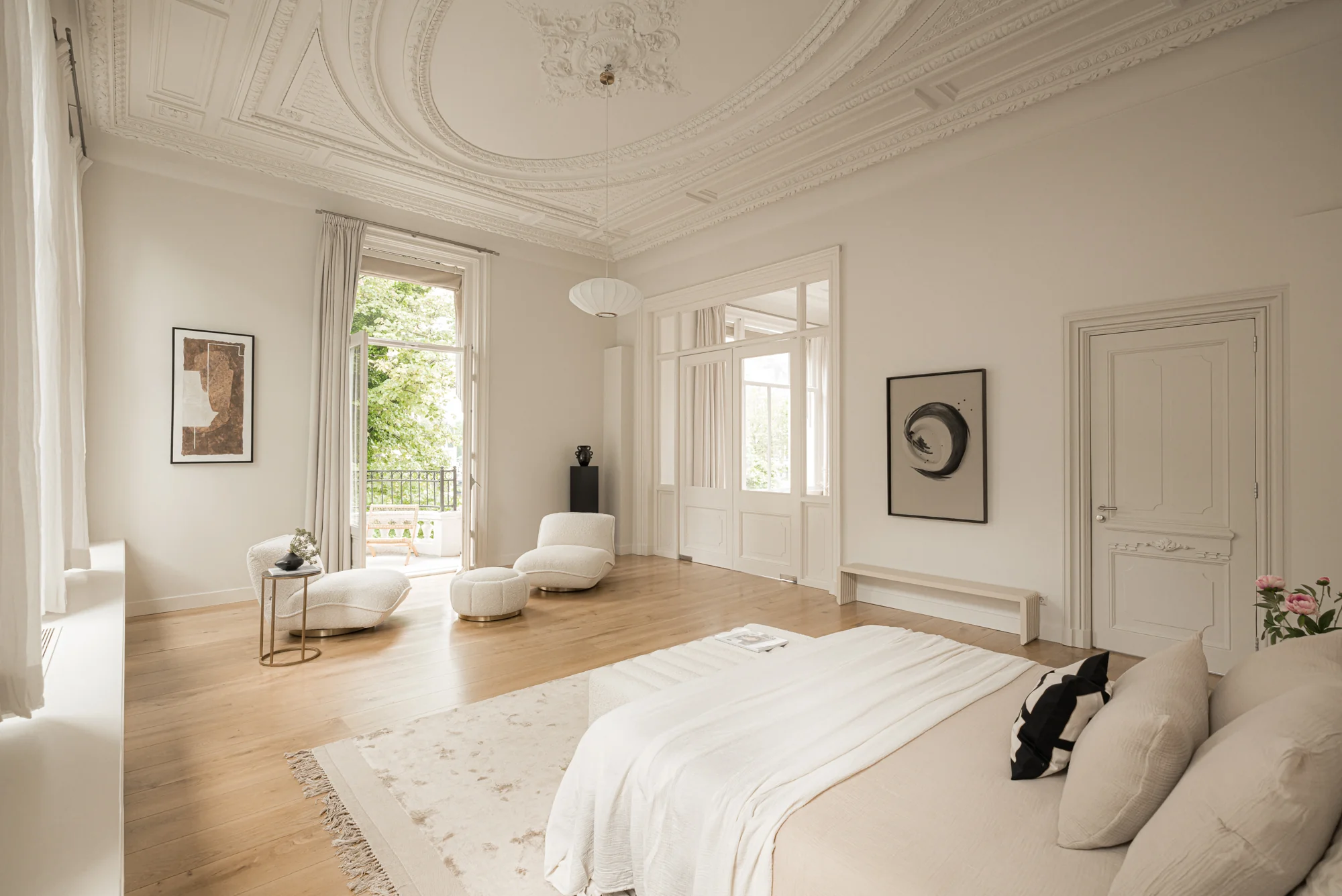 Licht en ruimtelijk ingerichte slaapkamer aan de Weteringschans met hoge plafonds, klassiek sierstucwerk en toegang tot een balkon.
