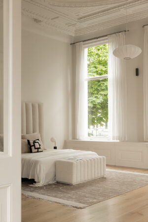 Licht en elegant ingericht slaapkamerinterieur aan de Weteringschans met hoge plafonds, grote ramen en neutrale tinten.