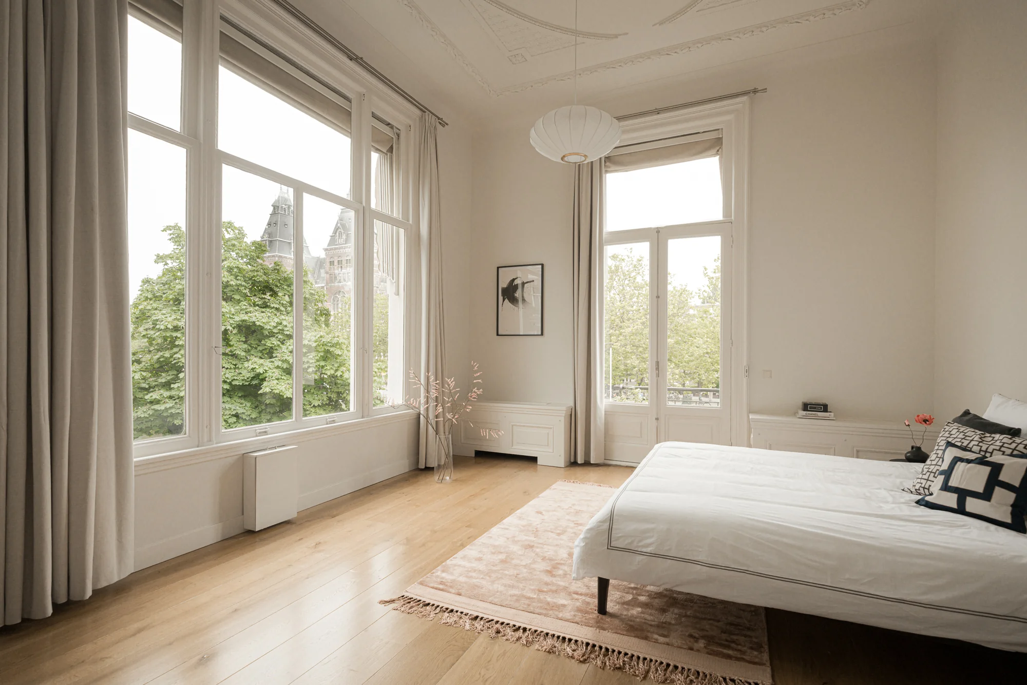 Lichte, minimalistische slaapkamer aan de Weteringschans met hoge ramen en uitzicht op het Rijksmuseum.