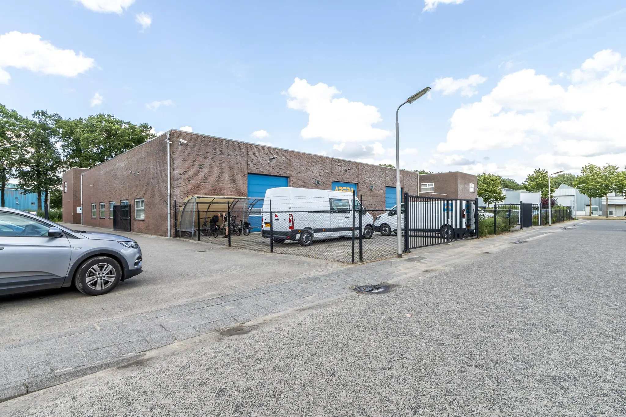 Bedrijventerrein aan de Terminalweg met een bakstenen pand, bedrijfsbusjes en overdekte fietsenstalling.